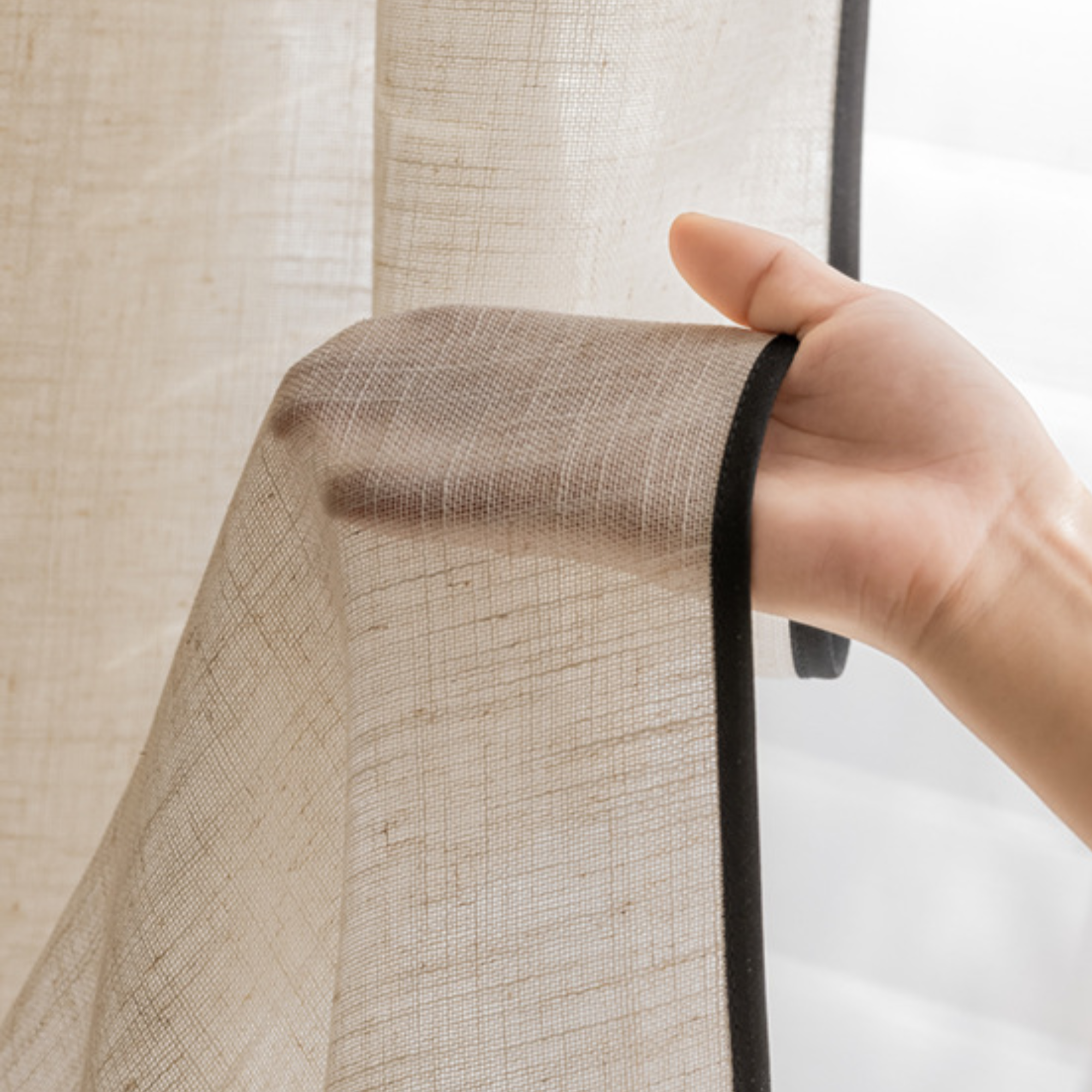 Natural linen sheer curtains with tailored black trim, showcasing fabric texture and elegant detail.