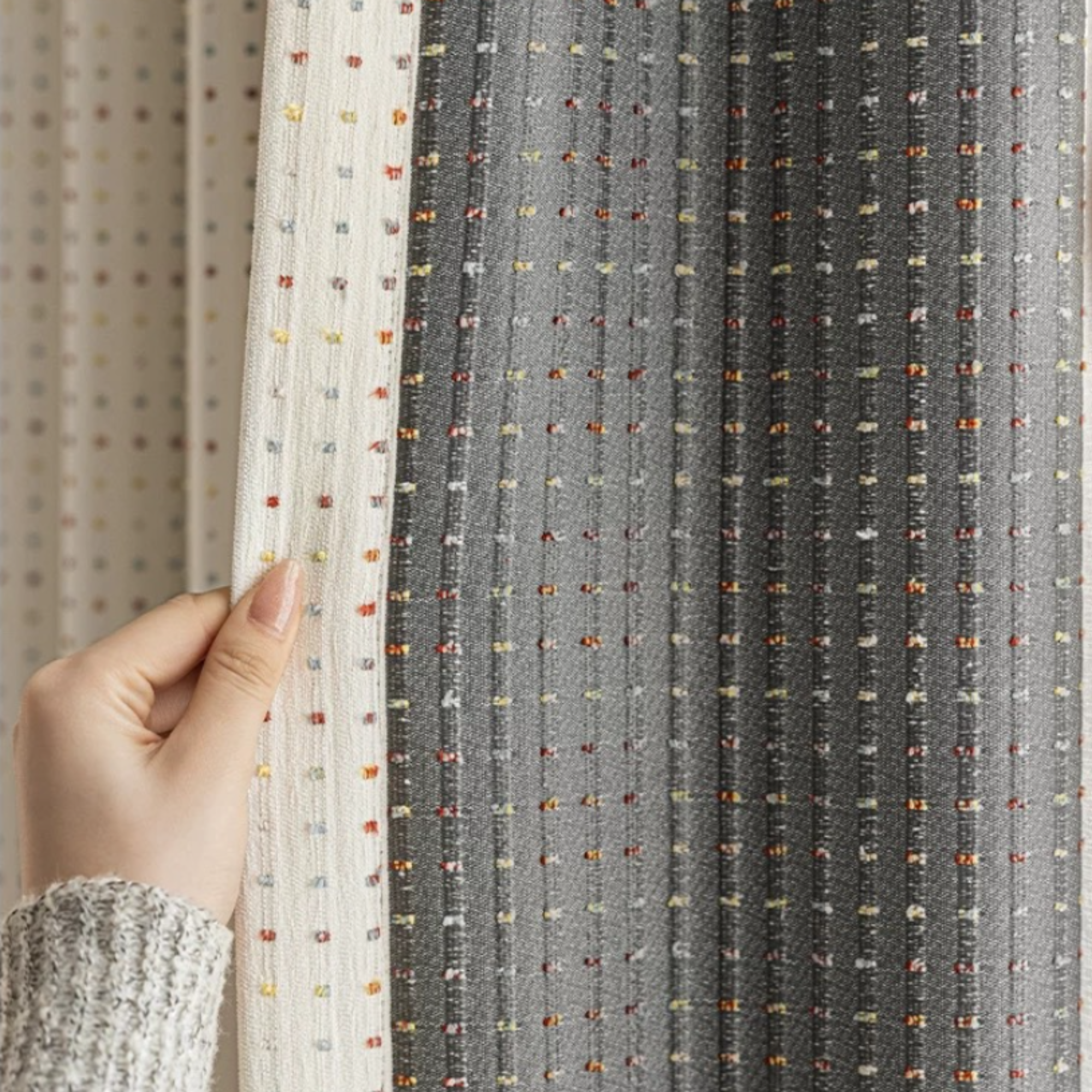 Close-up of a hand holding fabric with a textured pattern showing the backside of the curtain