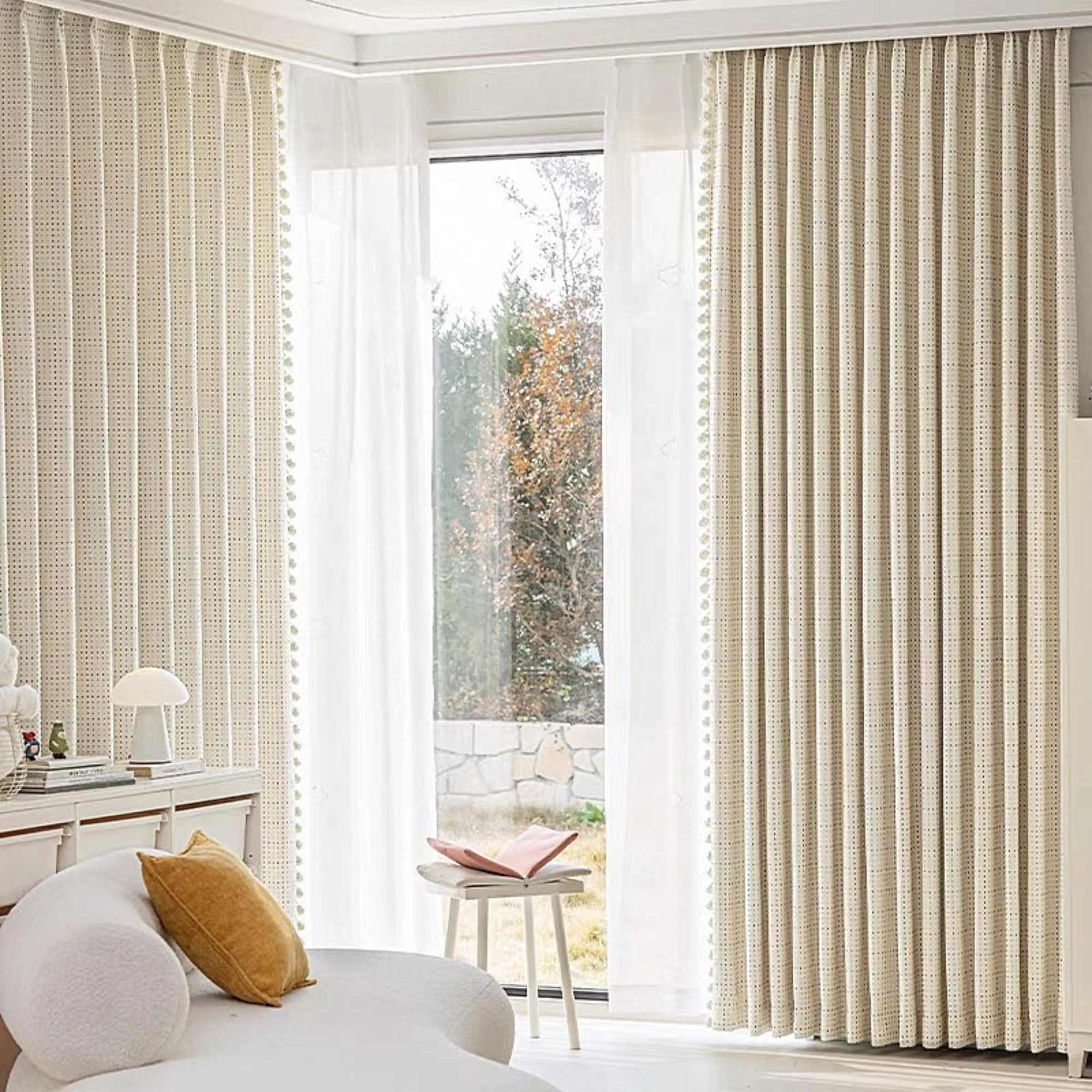 Luxury kids’ curtains with pinch pleats in a child's bedroom with a white sofa and small table.