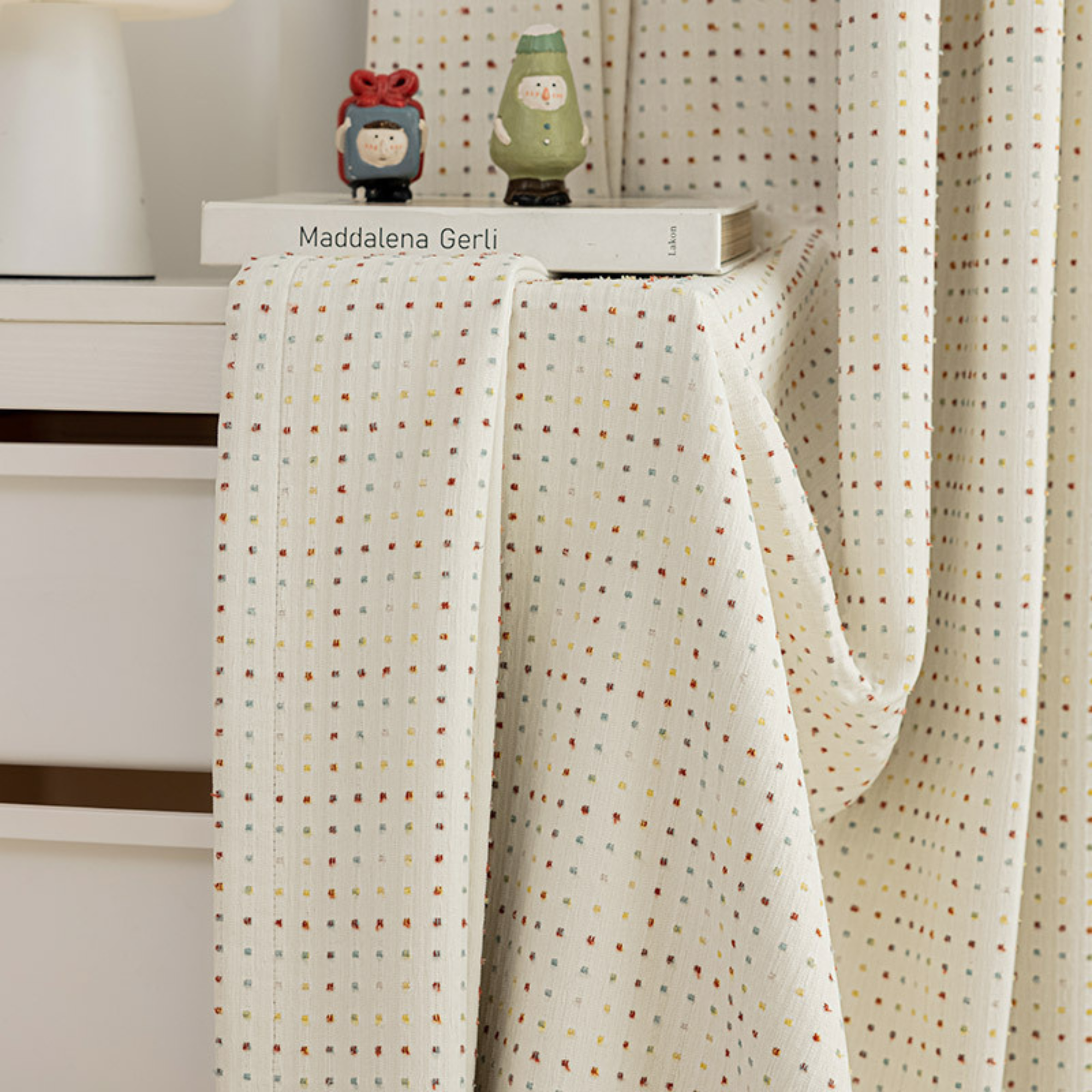 Room darkening kids curtains with a subtle dotted pattern draped over a white surface