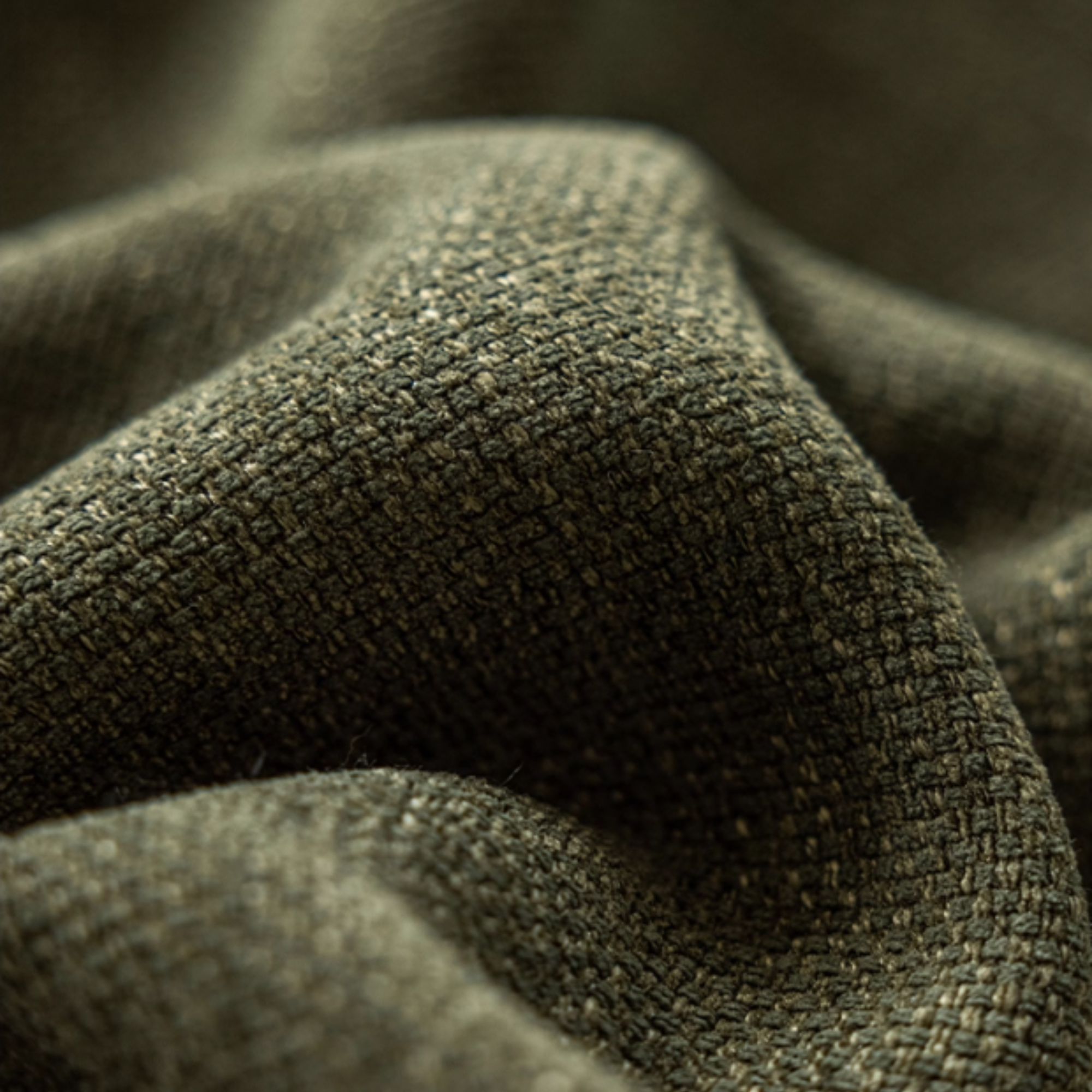 Close-up of textured green room darkening curtain fabric with a blurred background