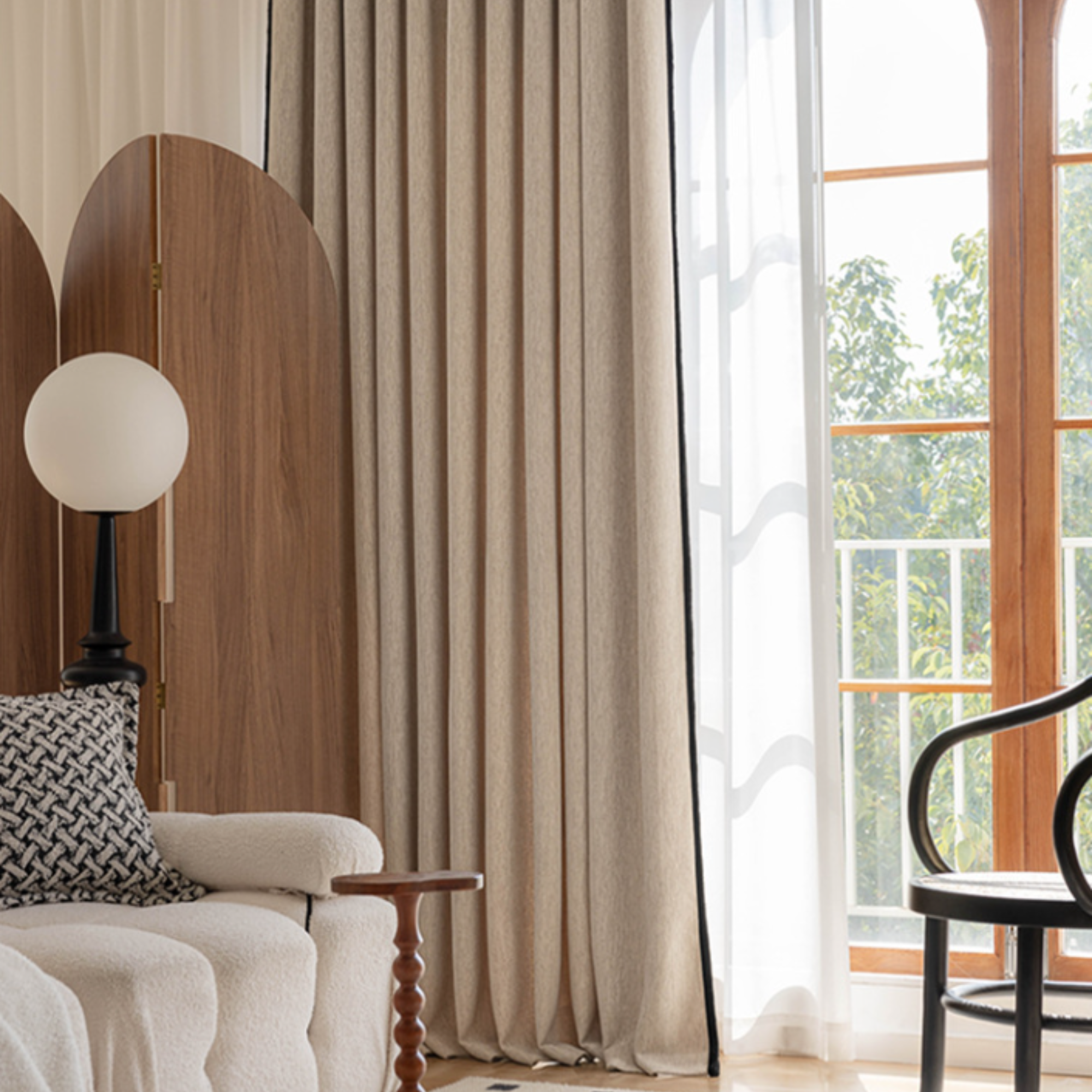 Living room with beige curtains with black trim, a white sofa, and a window view.