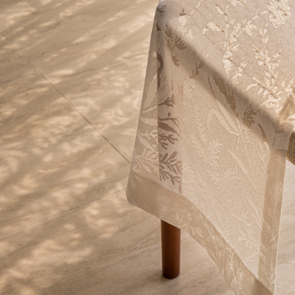 Beige lace curtain panel with floral pattern on a wooden chair