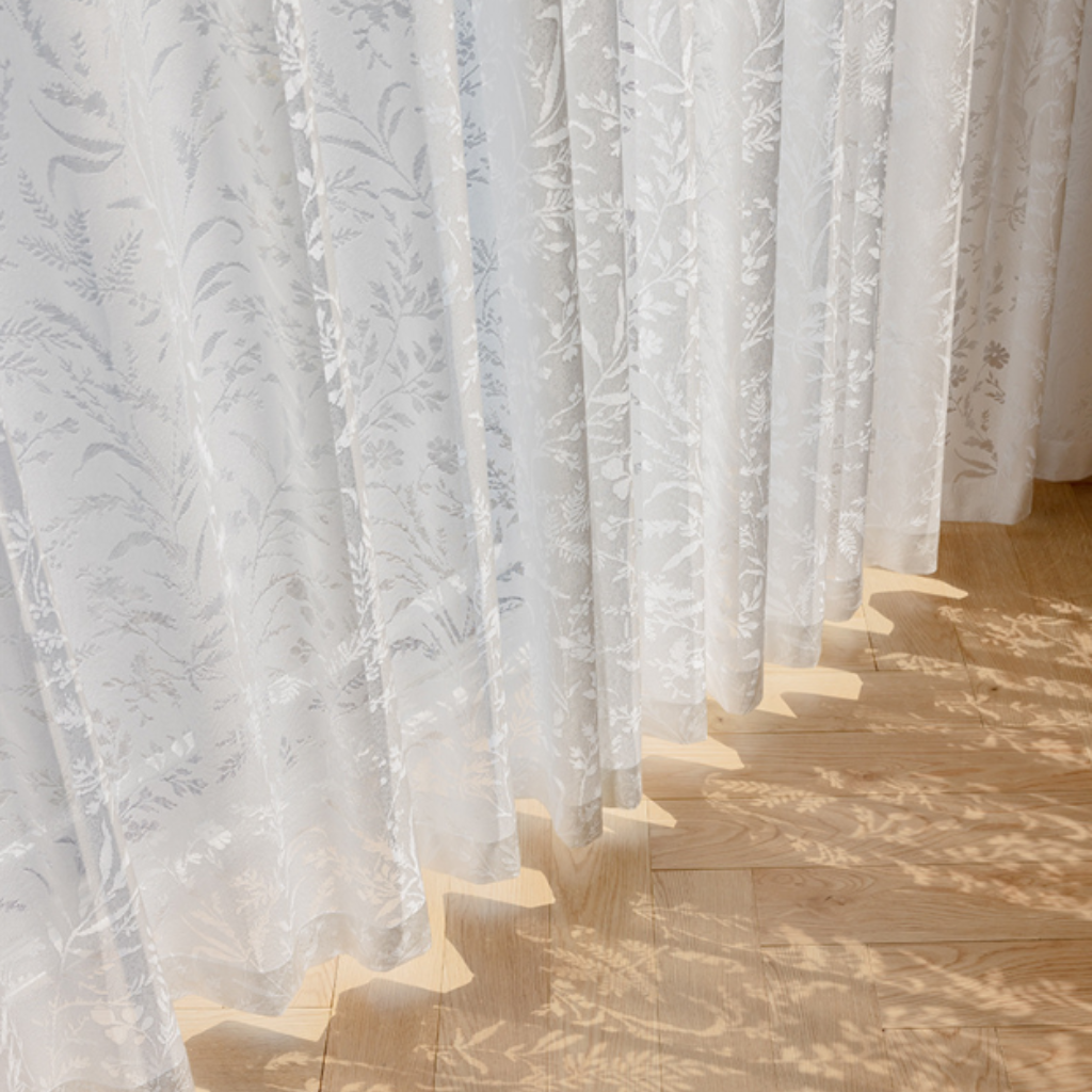 White lace curtains with a subtle pattern on a wooden floor in cottage core style