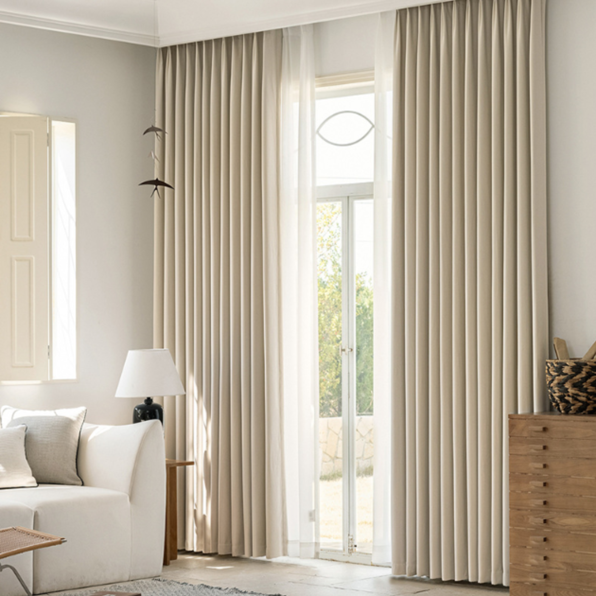 Beige blackout curtains in a living room with a white sofa and lamp.