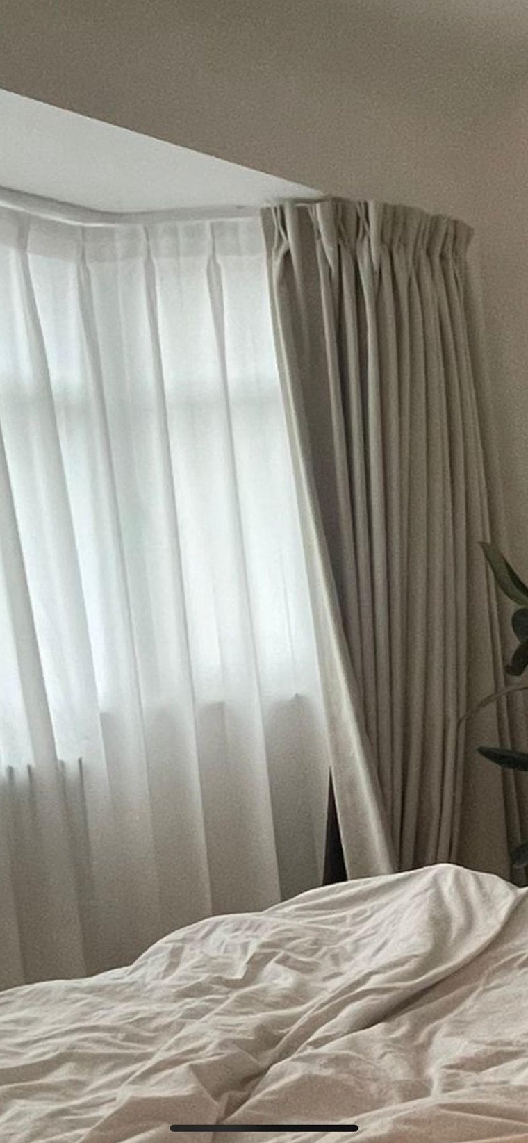 Beige blackout curtains in a room with a bed and plant