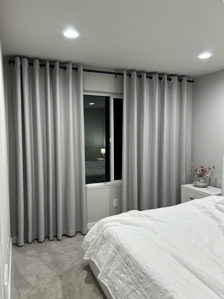 Bedroom with gray blackout curtains and a bed in a modern interior setting
