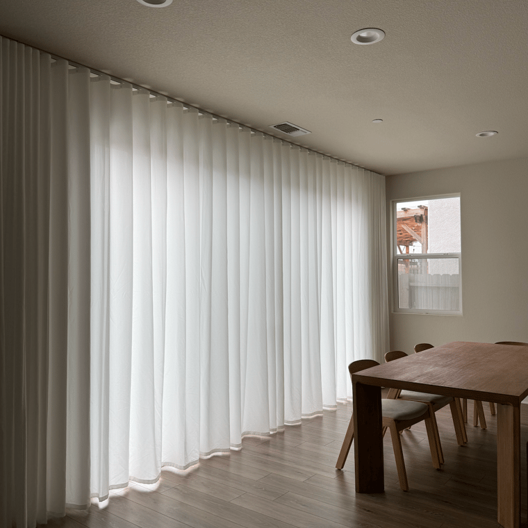 Modern interior with white privacy protecting custom curtains, wooden table, and chairs.
