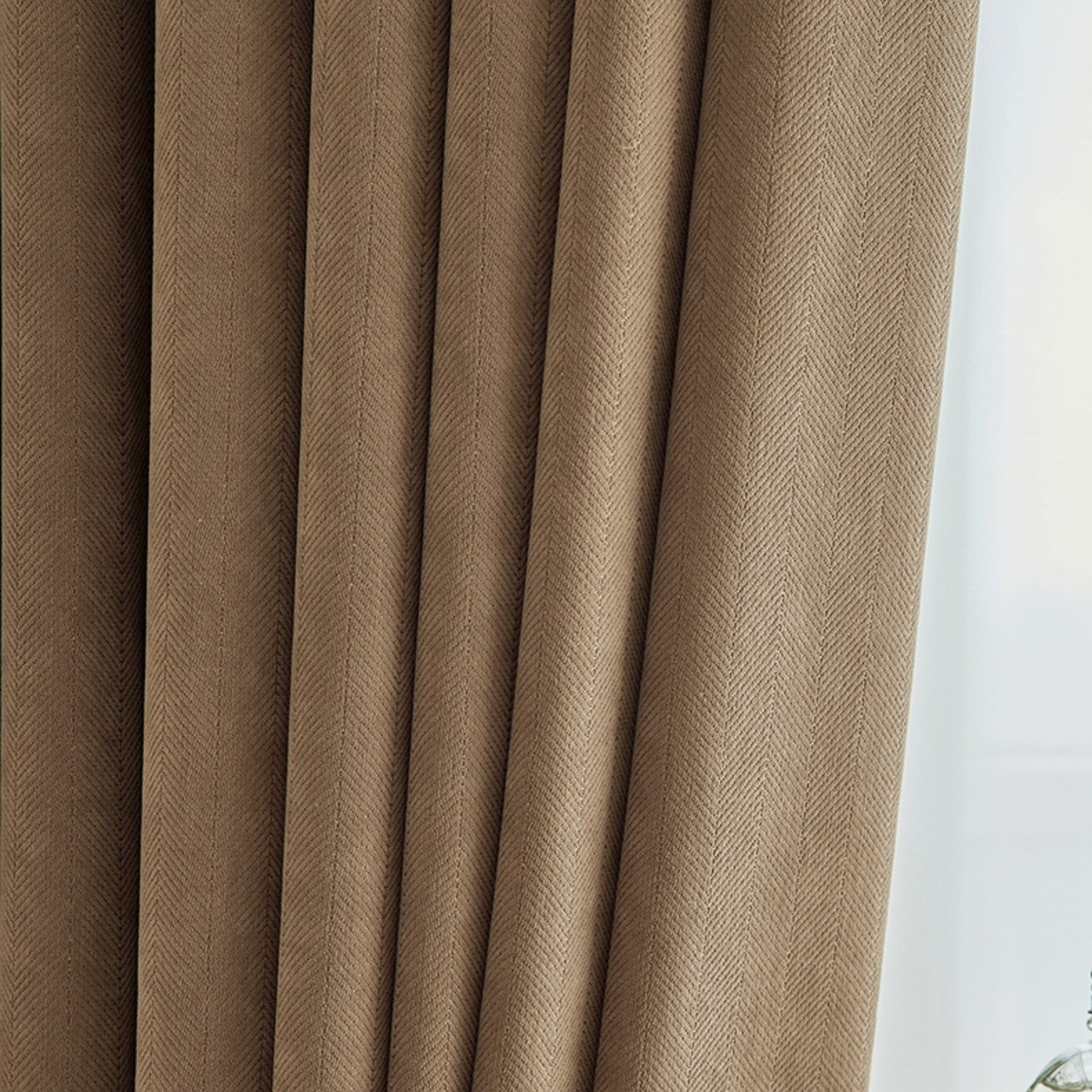 Close-up of brown curtains with a subtle herringbone texture.