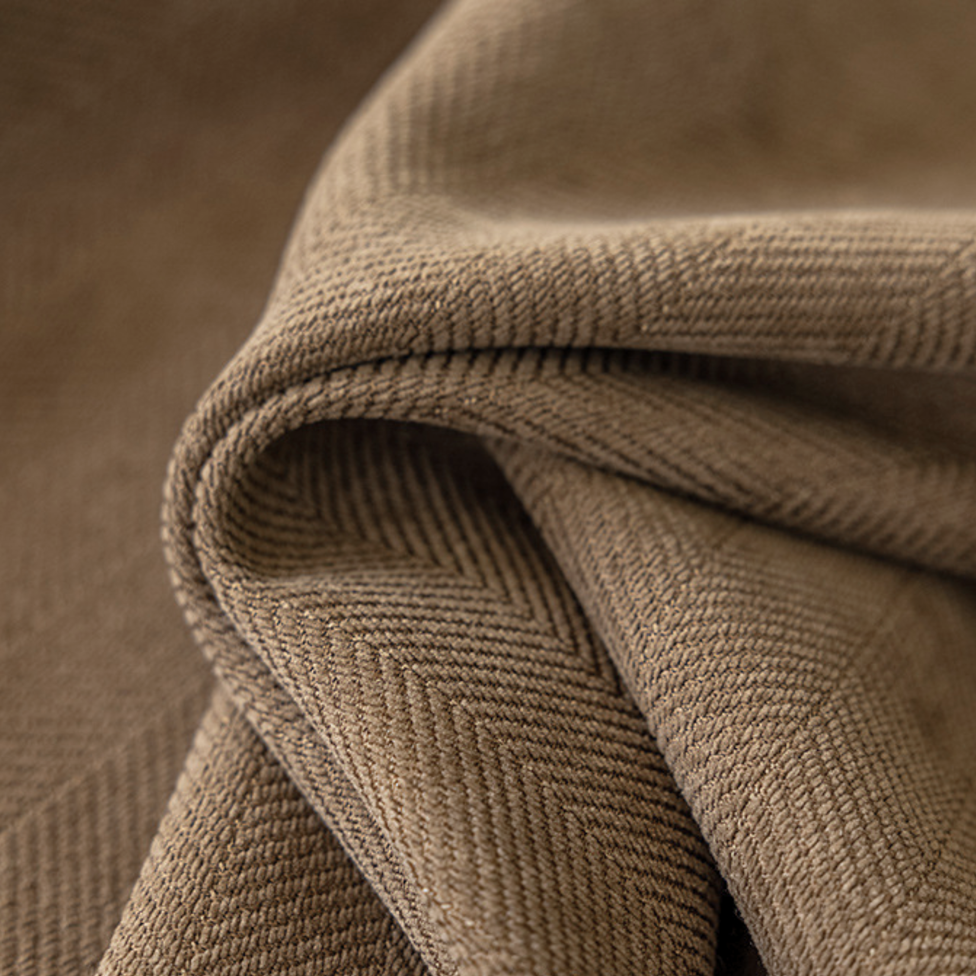 Close-up of a brown textured fabric with a herringbone pattern.