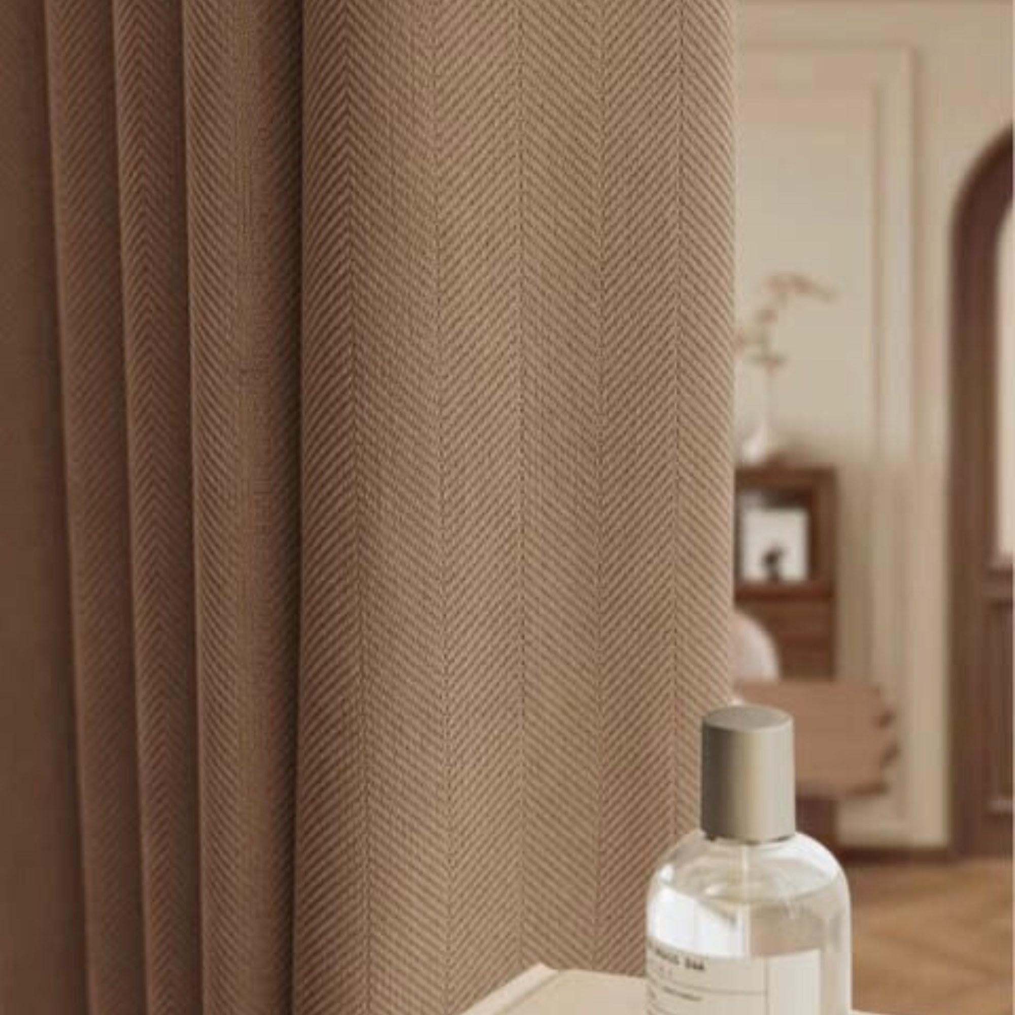Bottle of perfume on a surface with a herringbone textured brown curtain in the background