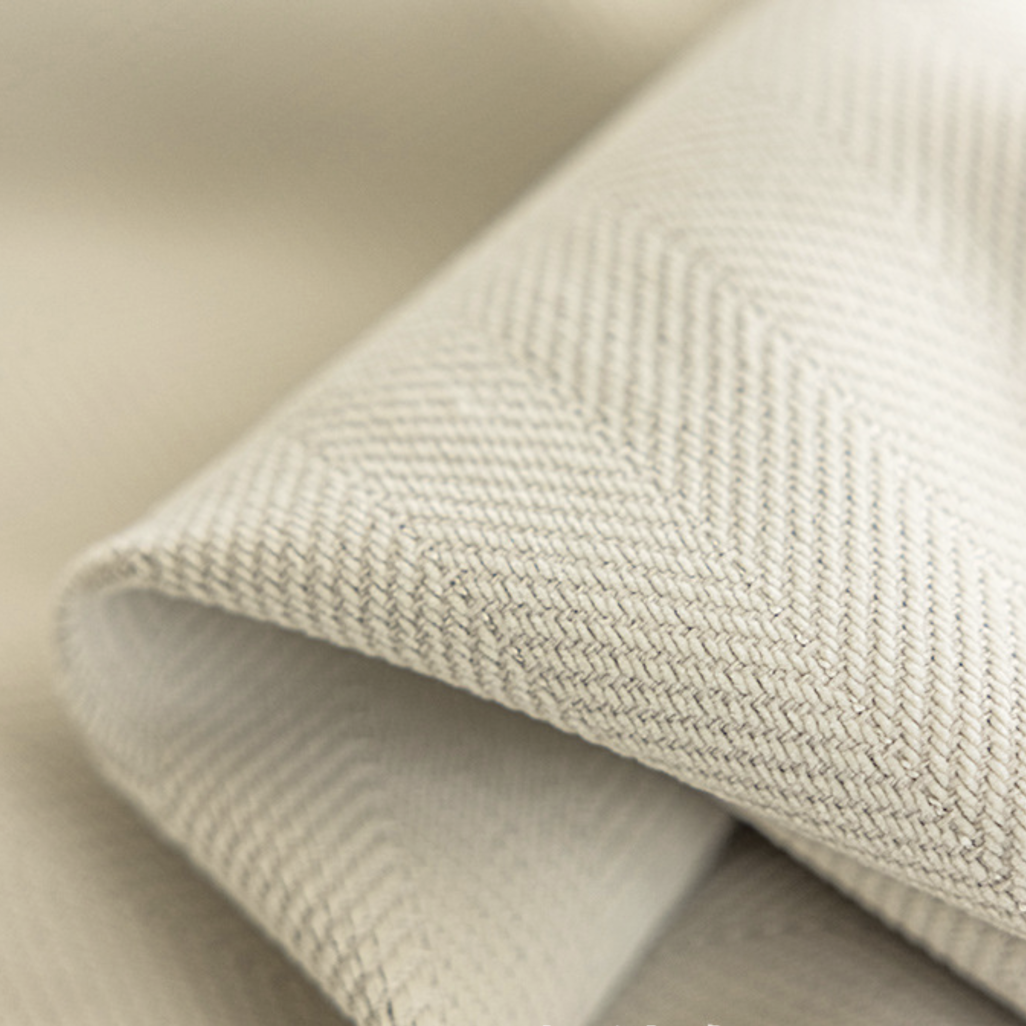 Close-up of cream fabric with a herringbone textured pattern