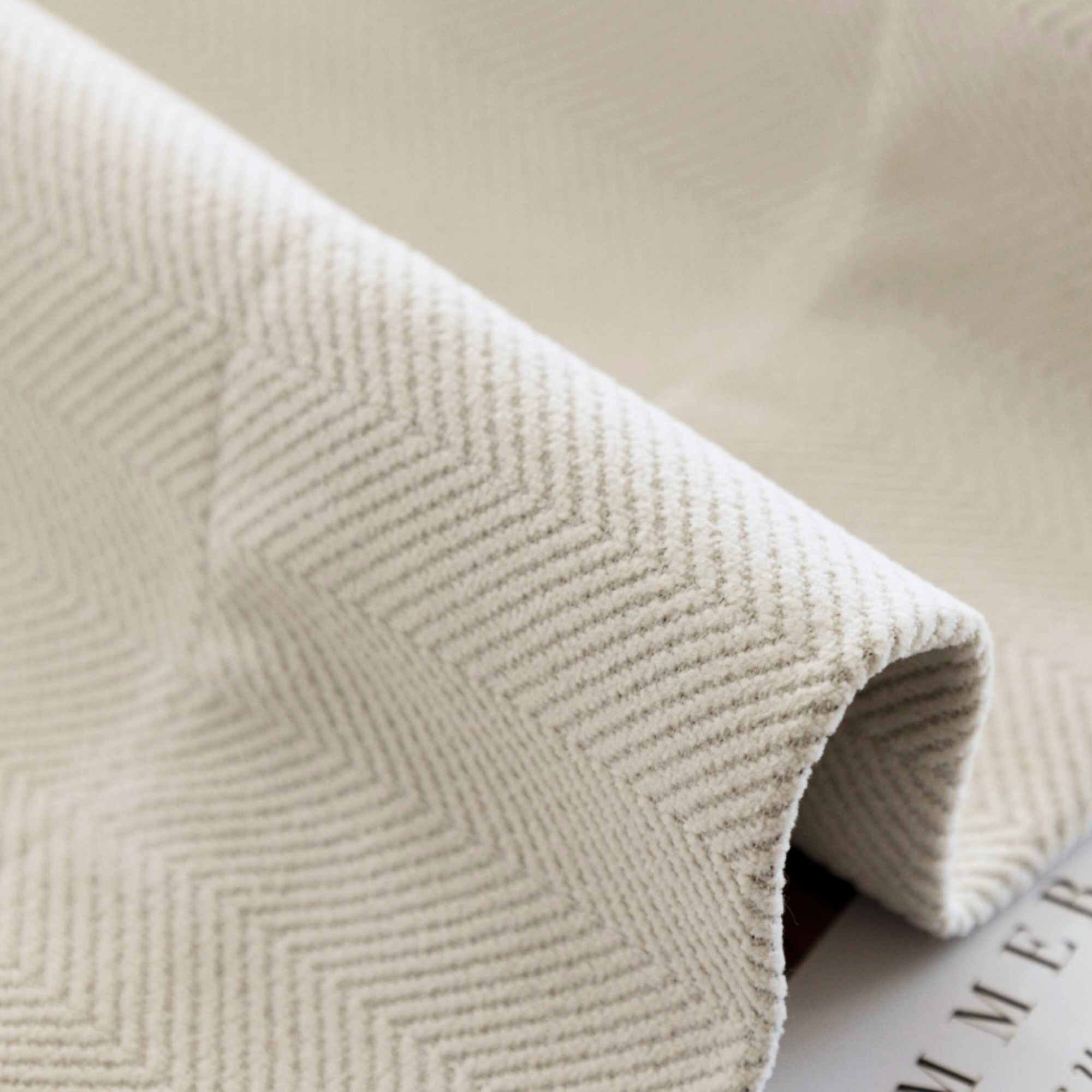 Close-up of a textured white fabric with a herringbone pattern.