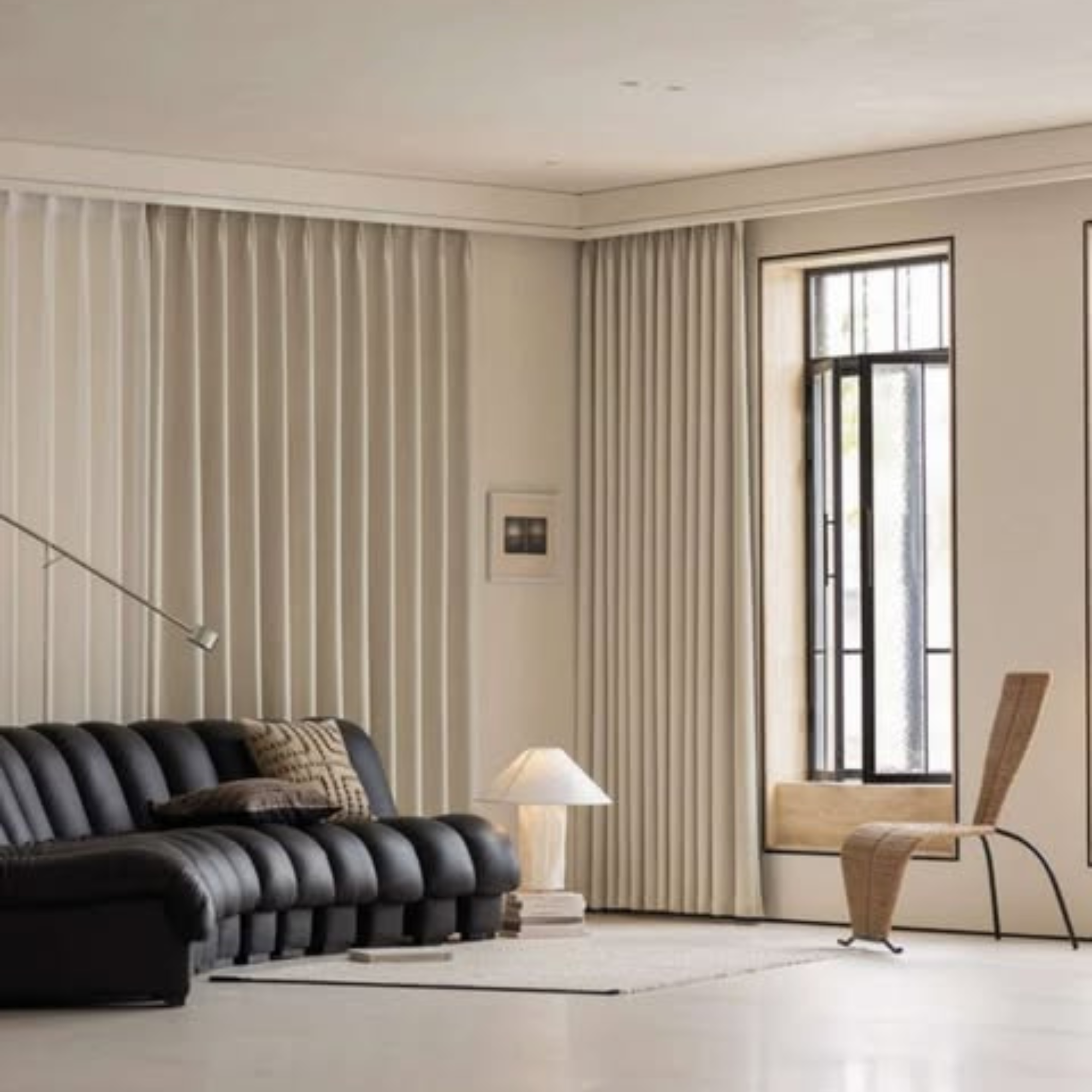 Modern living room with a black sofa, herringbone room darkening curtains, and a lamp.