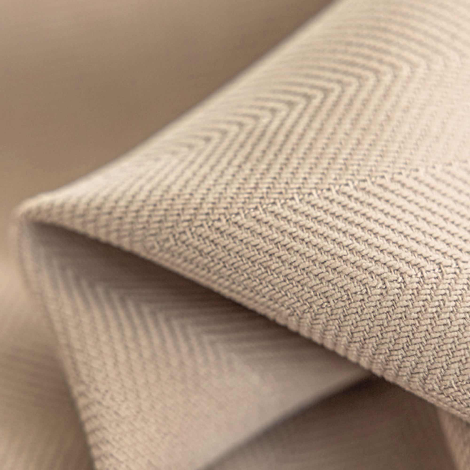 Close-up of beige textured fabric with a subtle herringbone pattern
