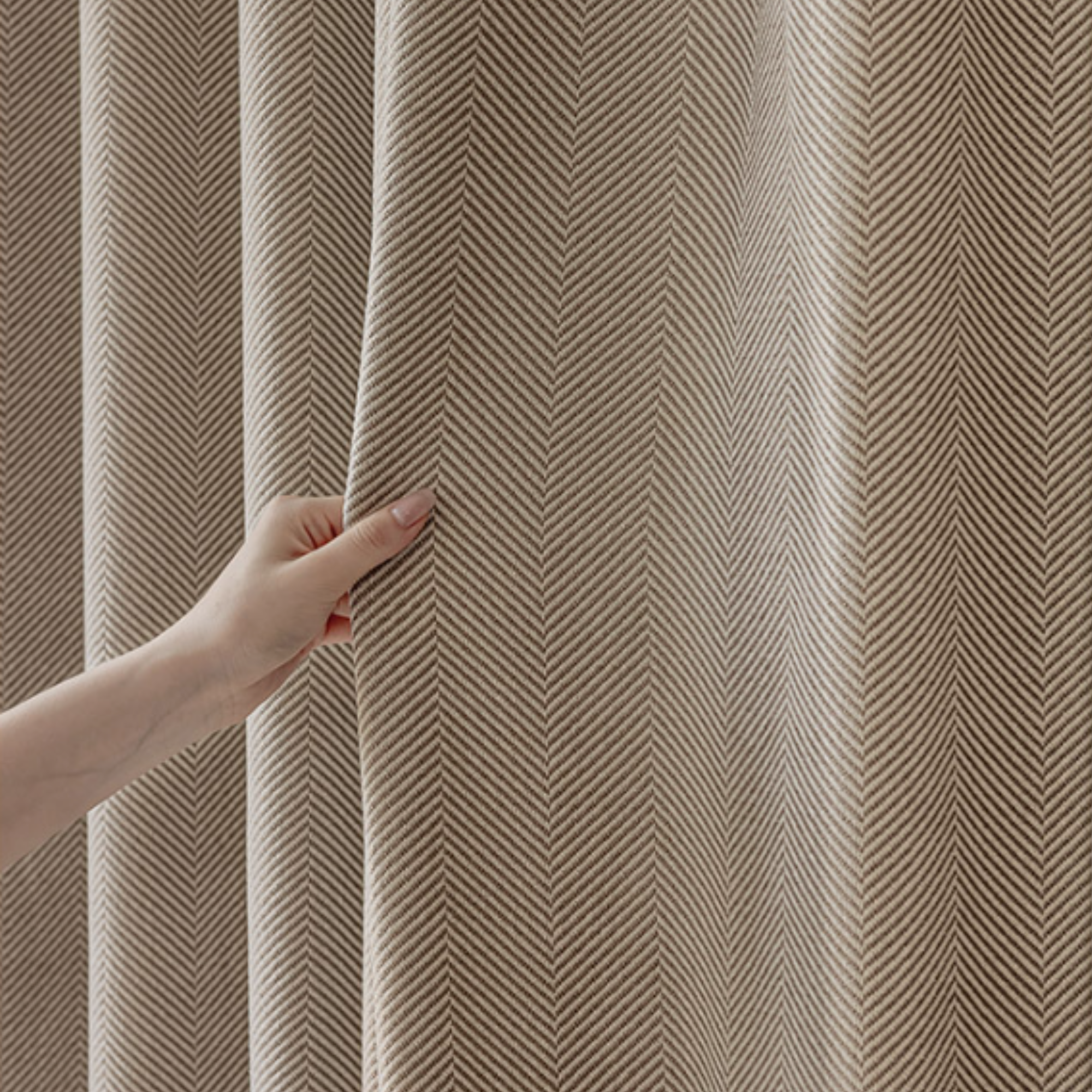 Hand touching a curtain with a herringbone pattern