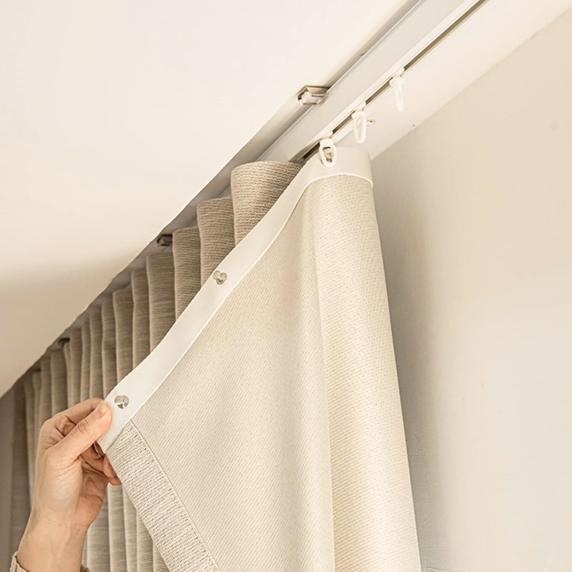 a hand installing ripple fold curtains on to track