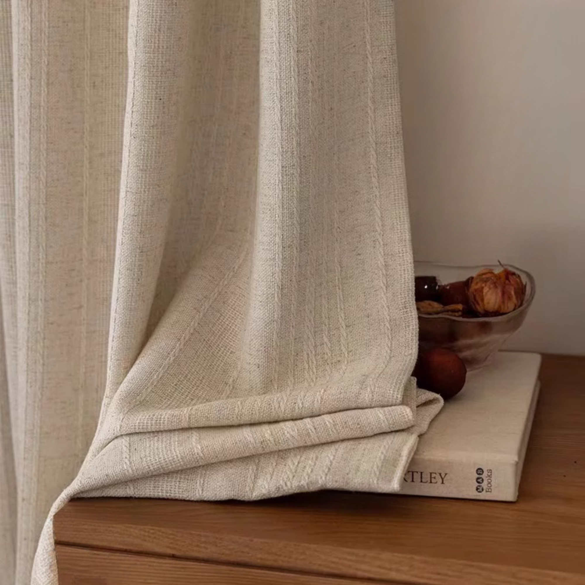 Textured white linen curtain panel draped over a wooden surface with a neutral background