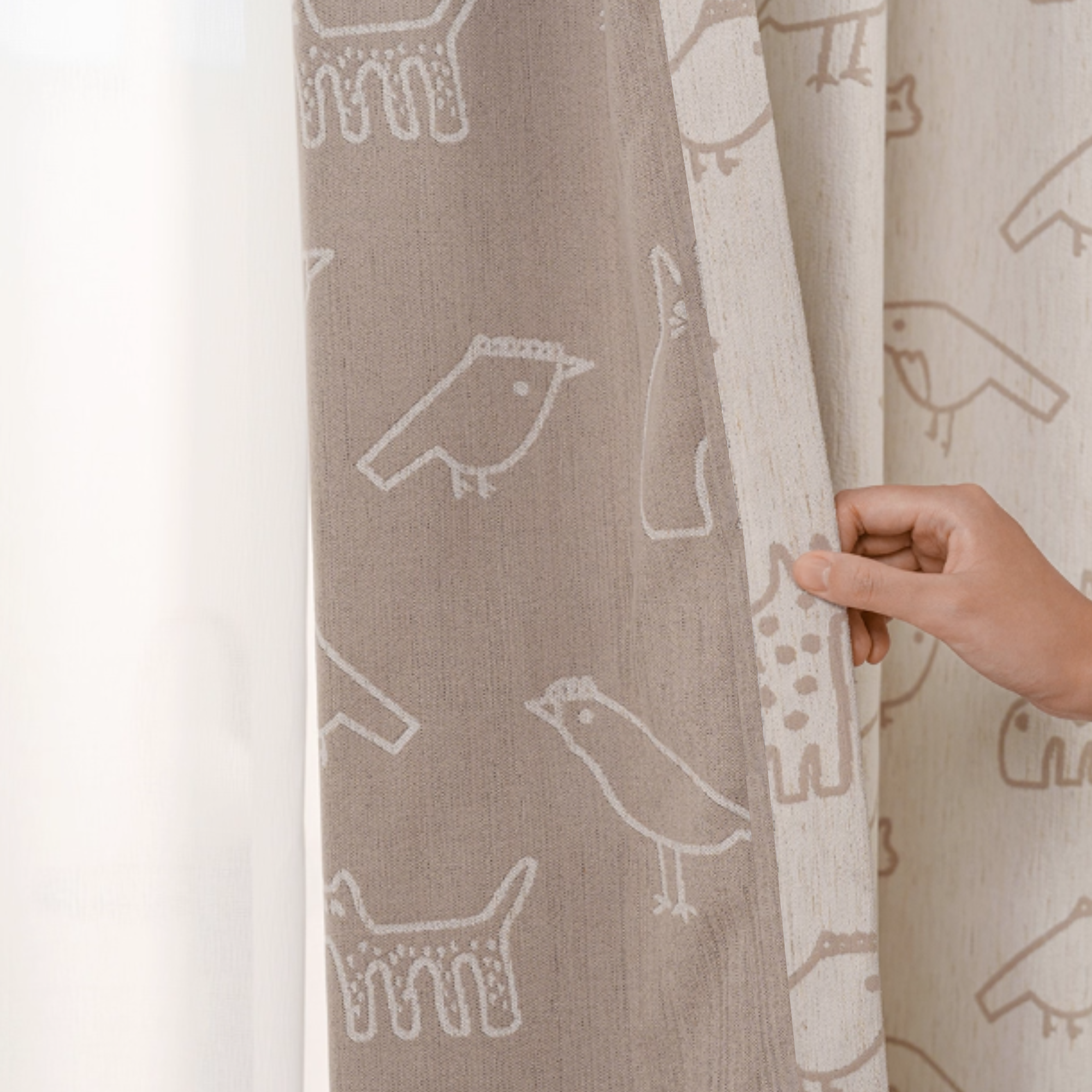 Kids' curtain with animal pattern held by a hand, showing the front and back side of the curtain