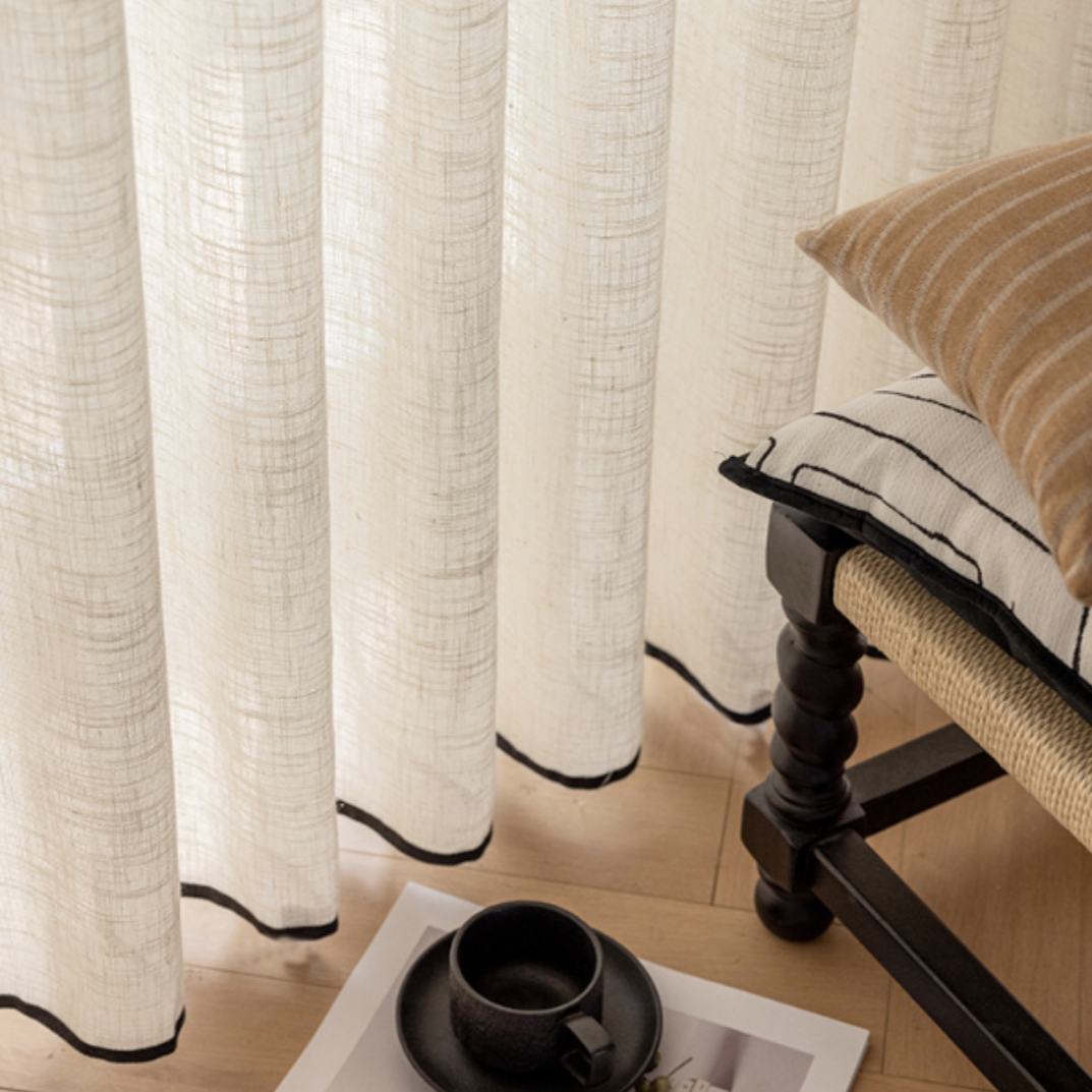 Linen textured curtains with black trim in a living room setting, showcasing its hem details.