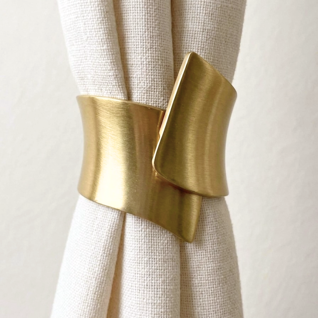 Gold curtain tieback on a beige curtain against a white background with a side angle