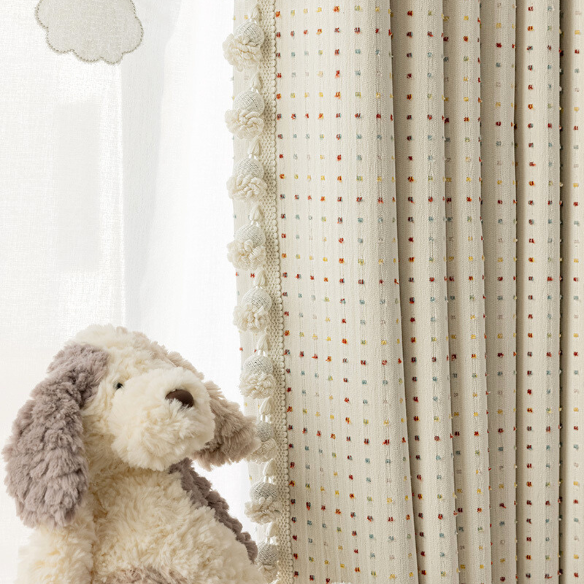 Rainbow polka dot blackout curtains for nursery next to a plush toy resembling a dog.
