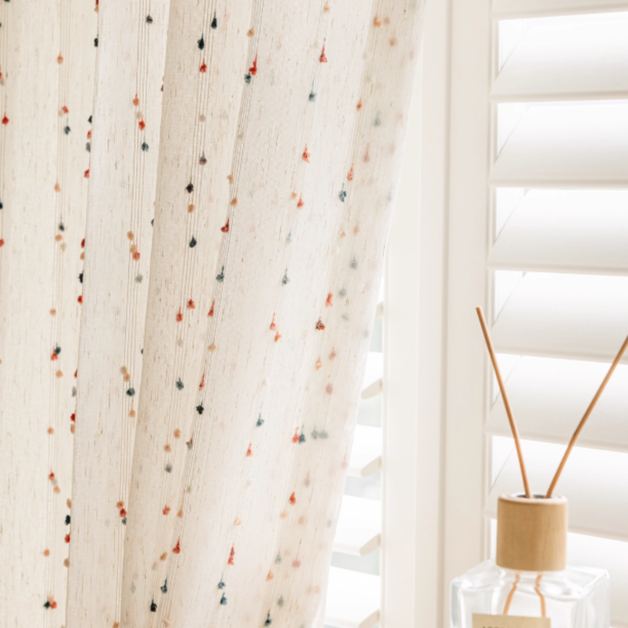 Sheer curtain with colorful dots in a room with a diffuser