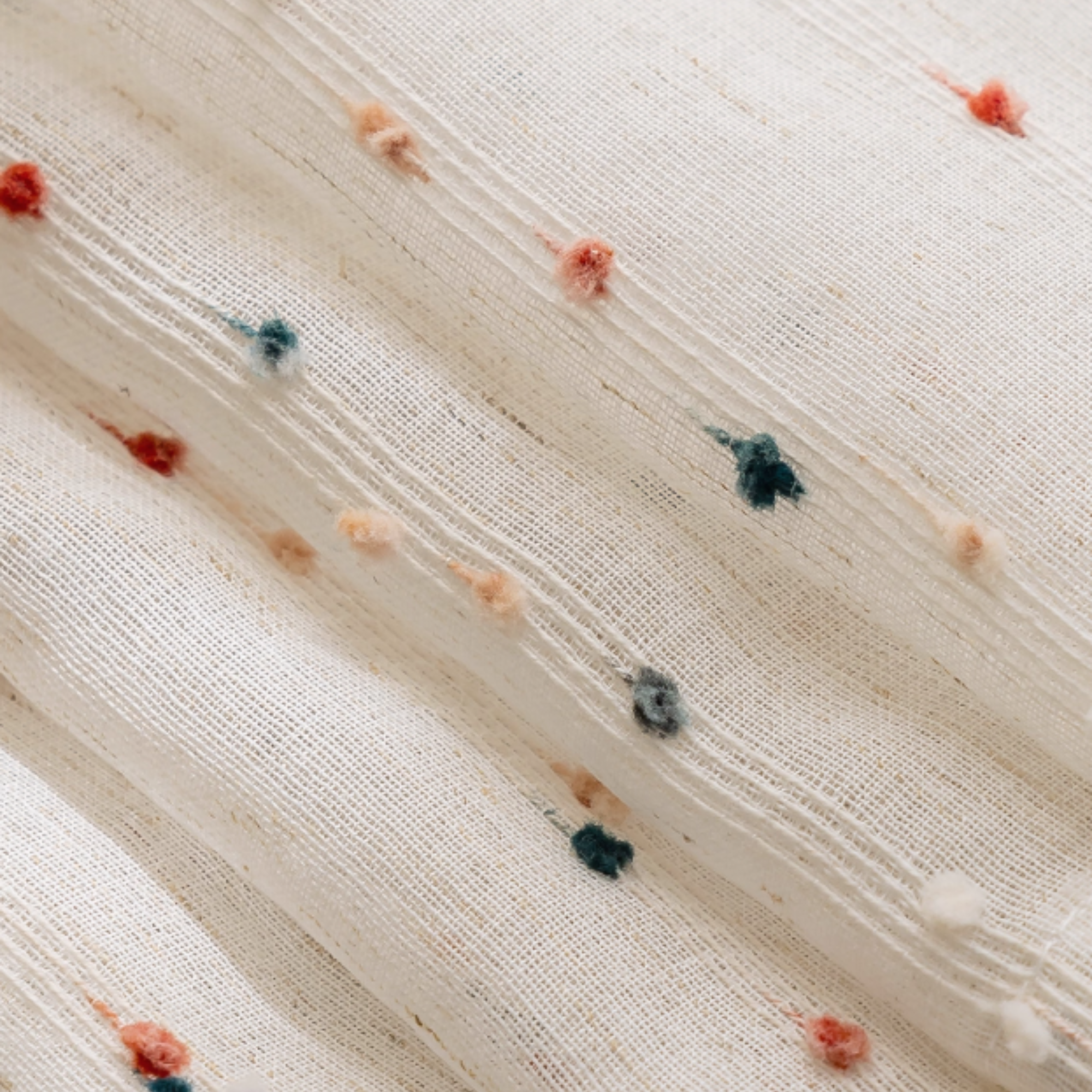 Close-up of textured fabric with small colorful pom poms