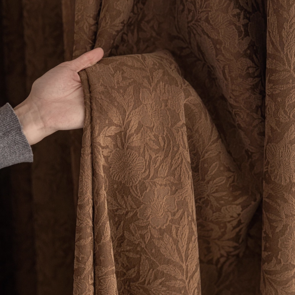 Brown floral blackout curtains with a hand holding it
