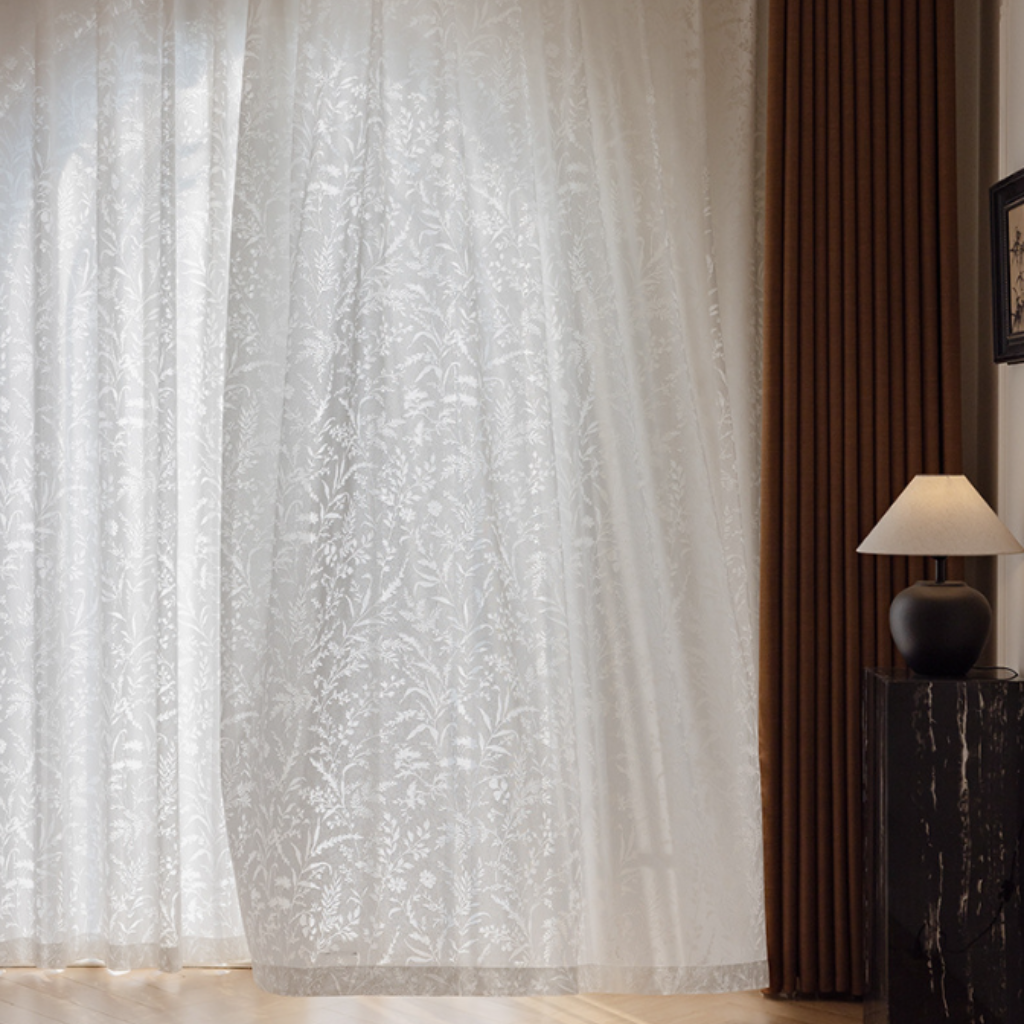 Sheer white curtain with floral pattern in a living room paired with brown blackout curtains