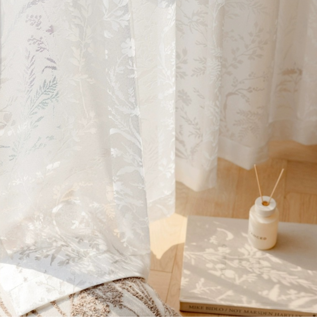 White lace curtain with a small table and diffuser in the background