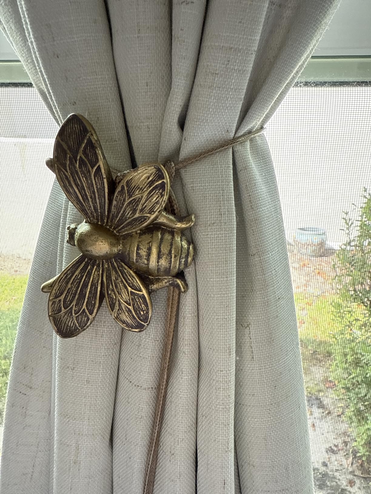 Bronze bee-shaped curtain tieback on a beige curtain