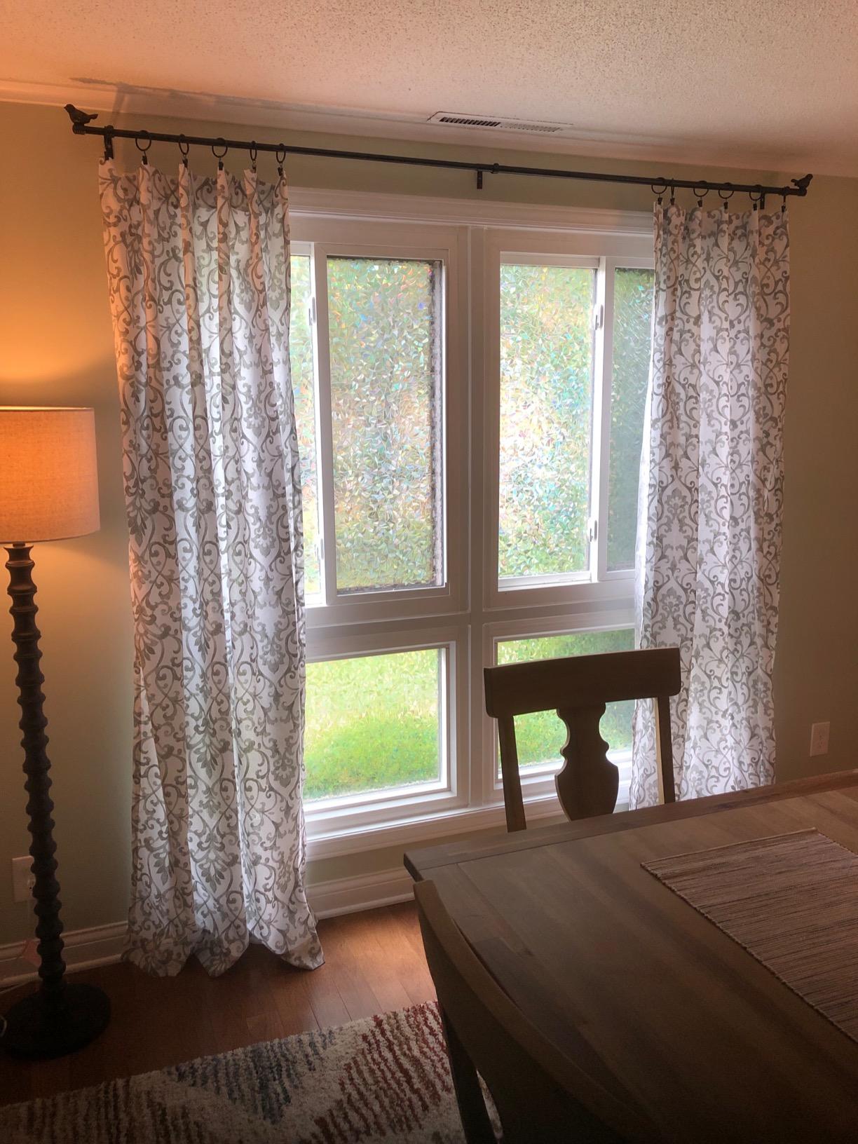 Living room with floral curtains on a rod with bird details, lamp, and table.