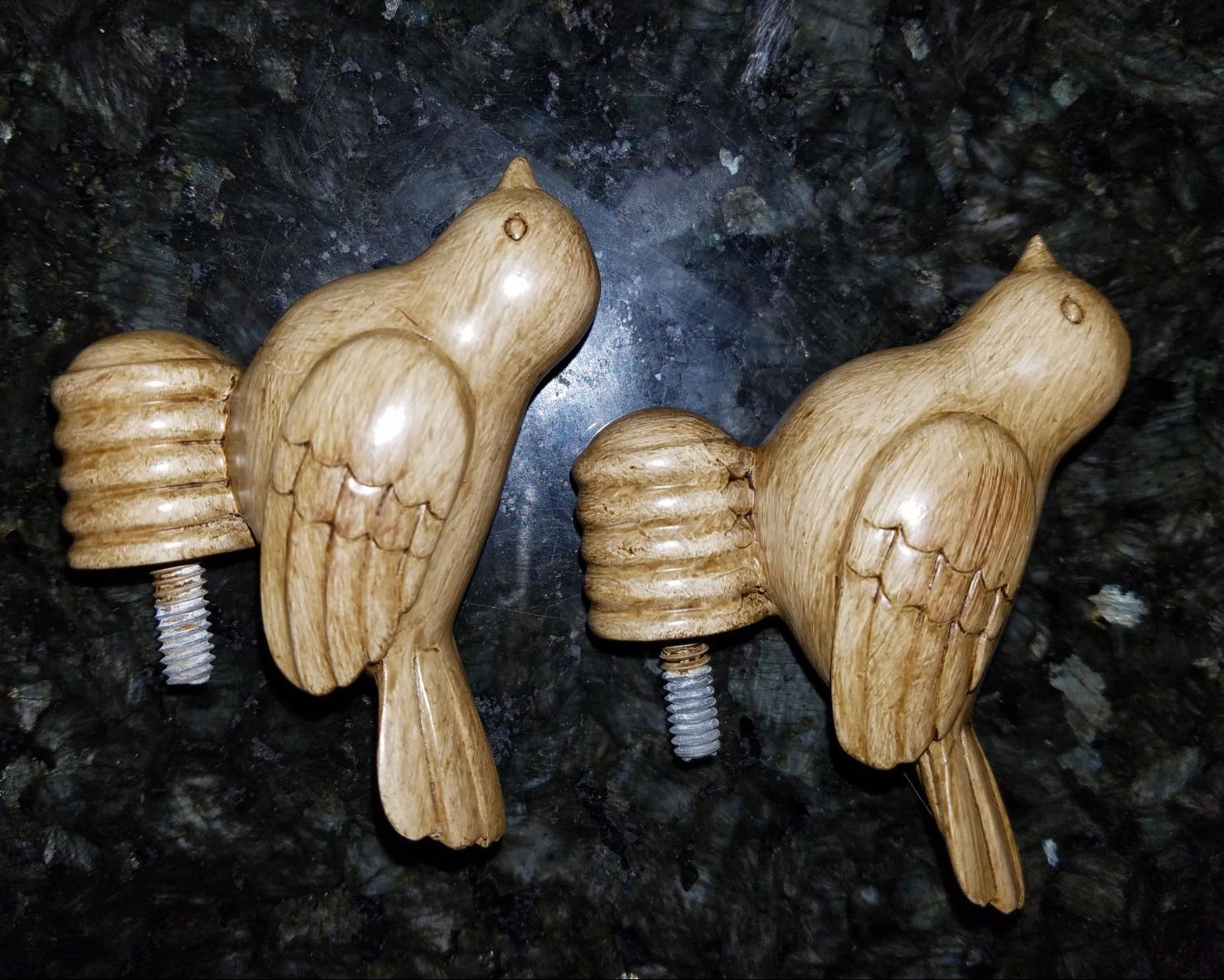 Two wooden bird-shaped drapery rod ends on a dark textured background