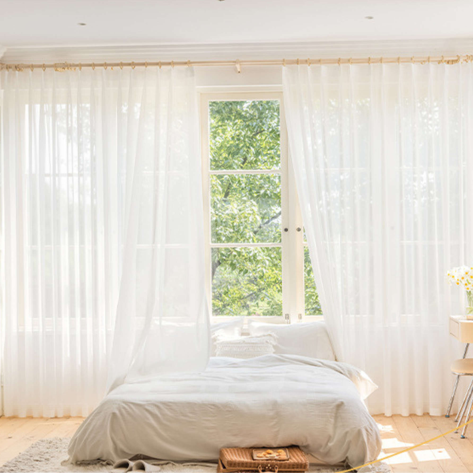 Bedroom with white bedding and sheer curtains in a bright room