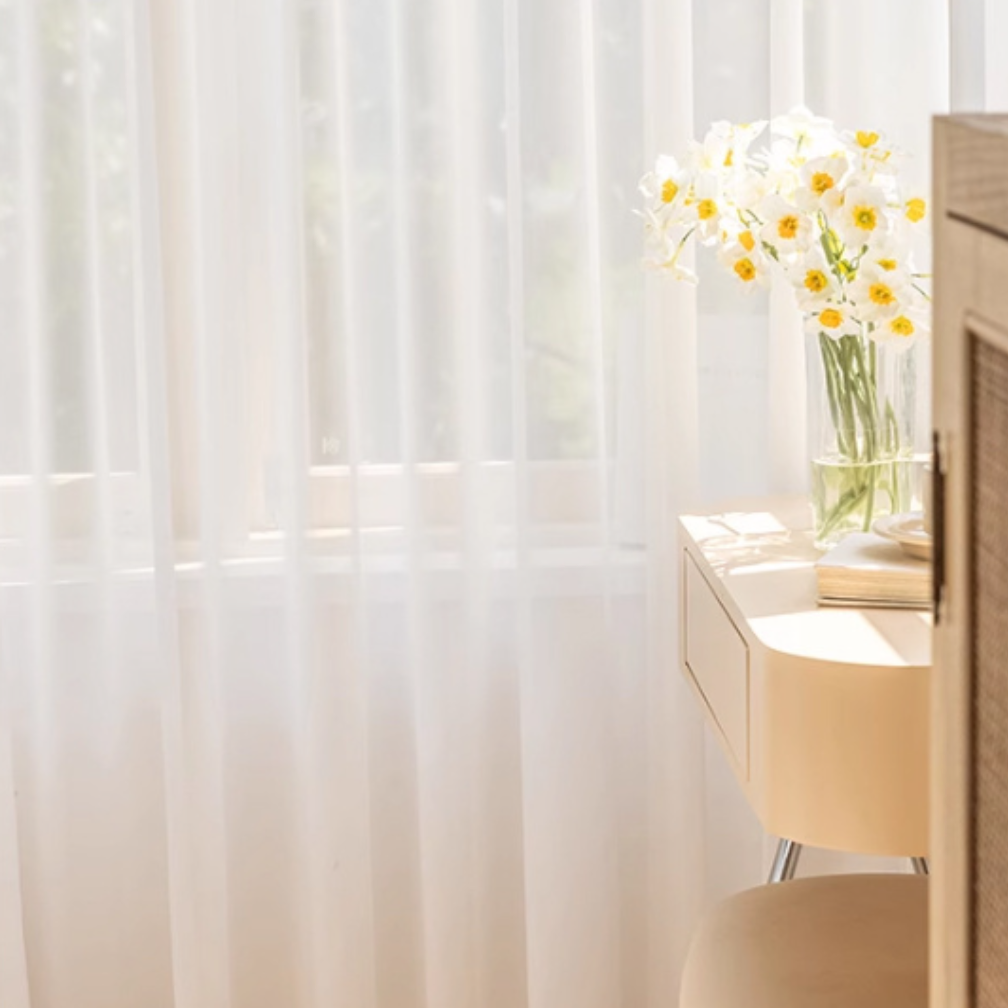 Sheer white curtain with a vase of flowers on a table in the background
