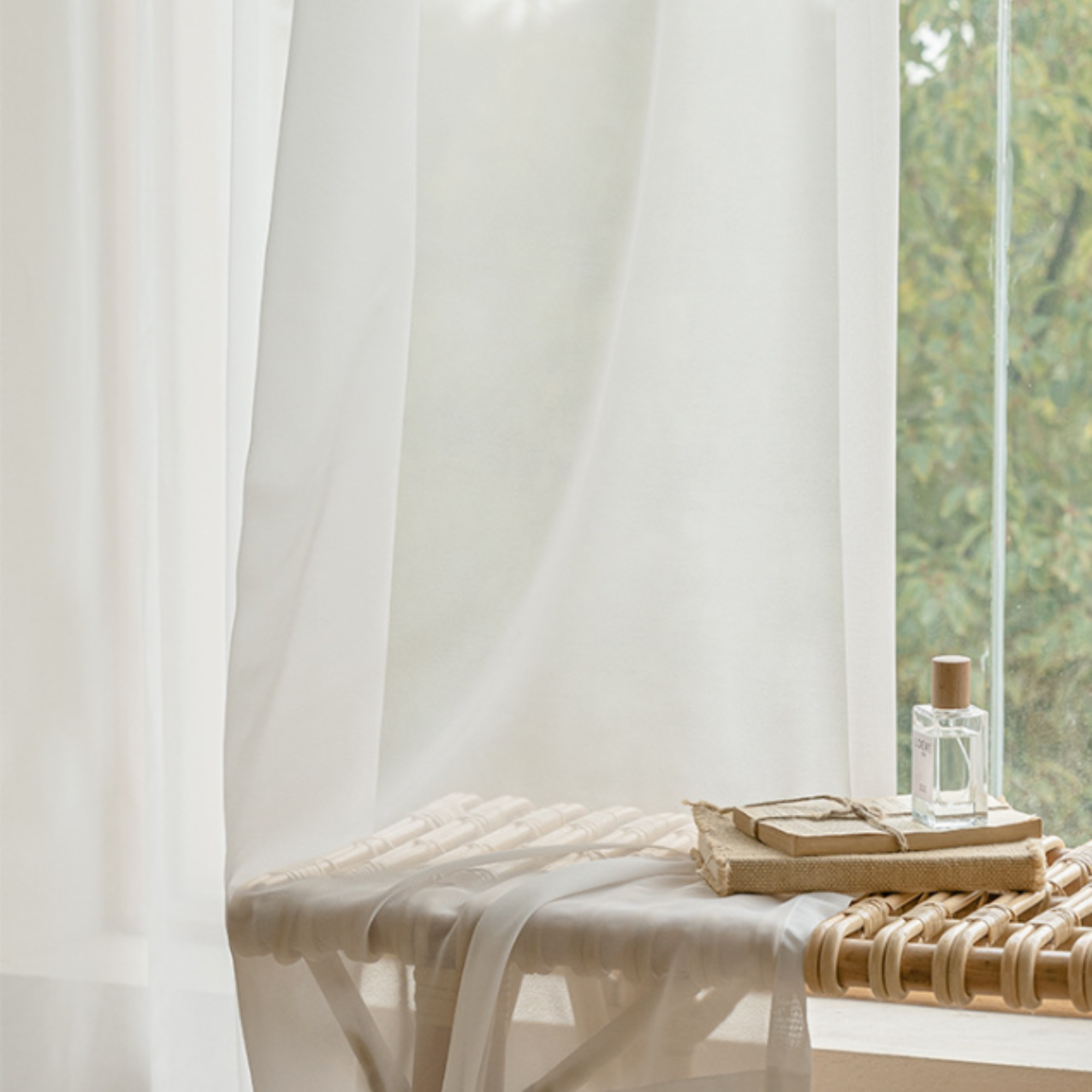 White curtains with a wooden bench and decorative items in a bright room.