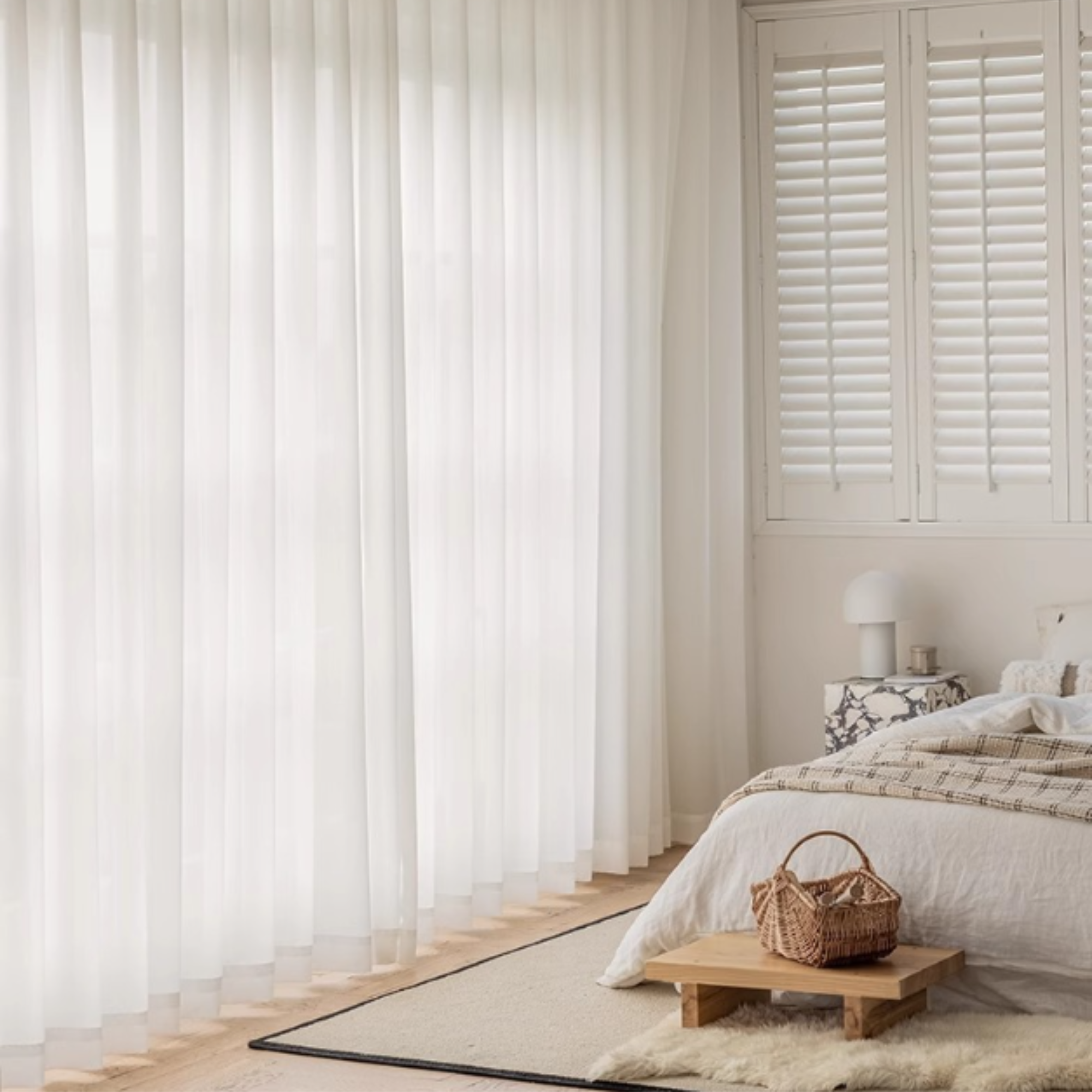 Bedroom with white privacy sheer curtains, wooden bench, and basket.