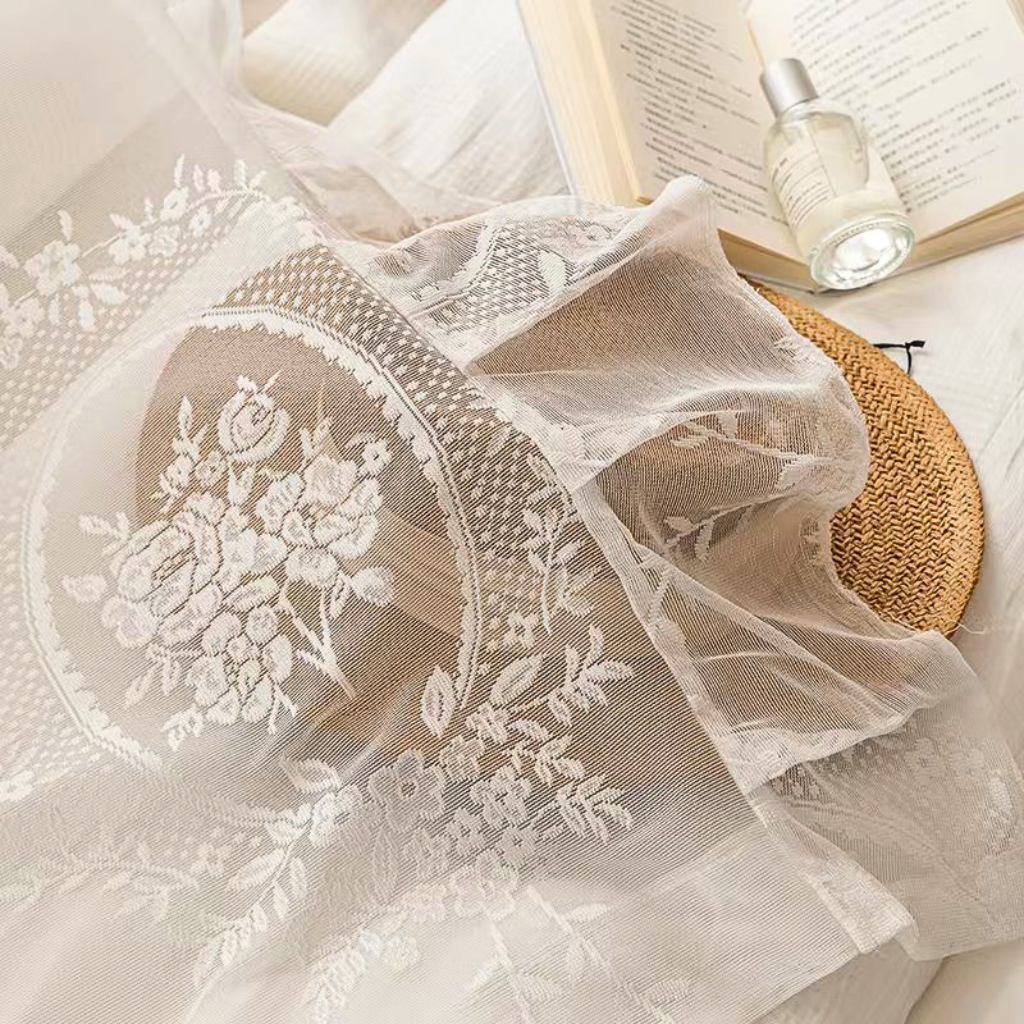 White floral lace fabric closeup with ruffled trim detail.
