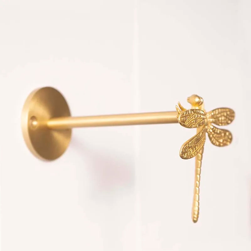 Gold drapery holdback with dragonfly design on a white background