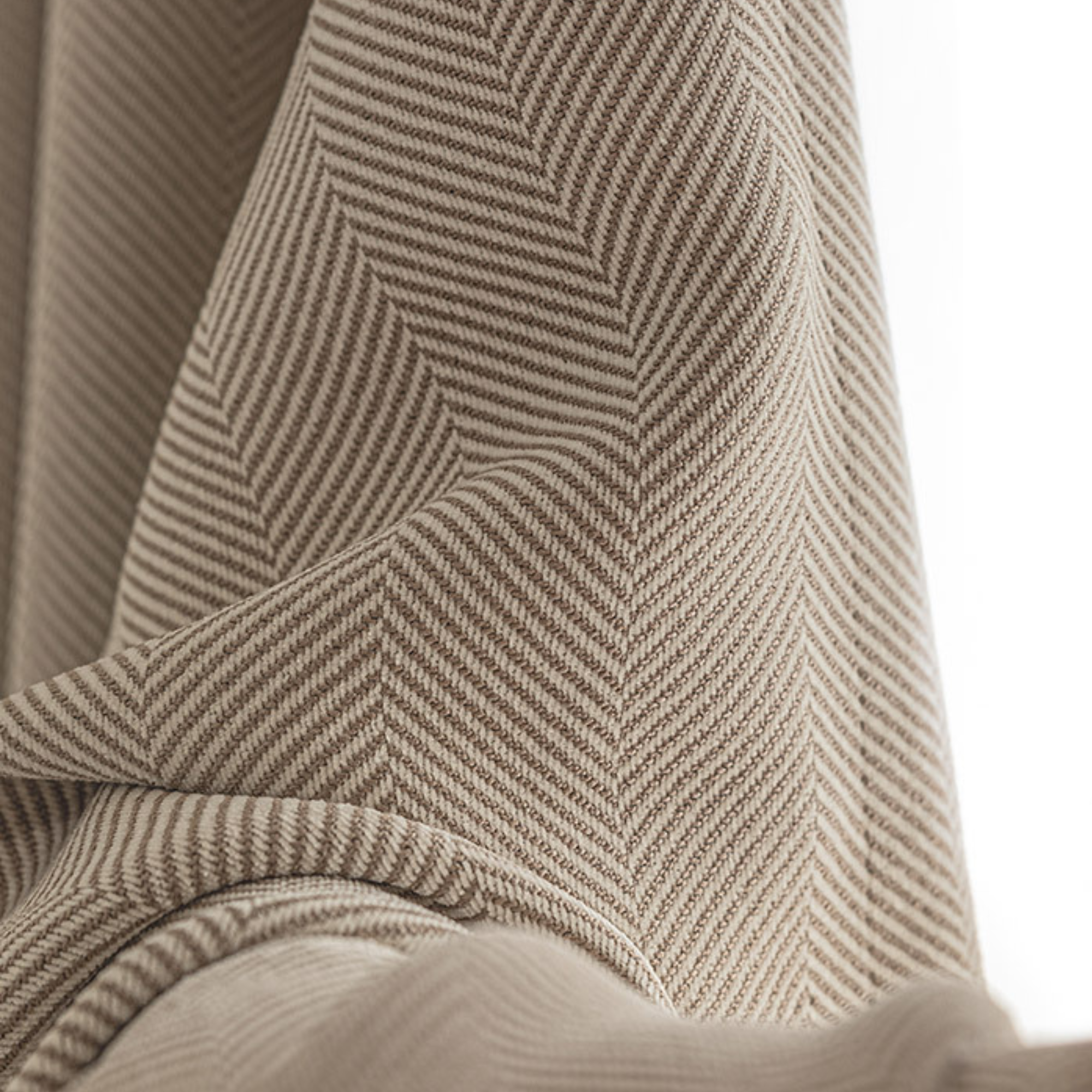 Close-up of a textured fabric with a herringbone pattern in beige and brown tones.