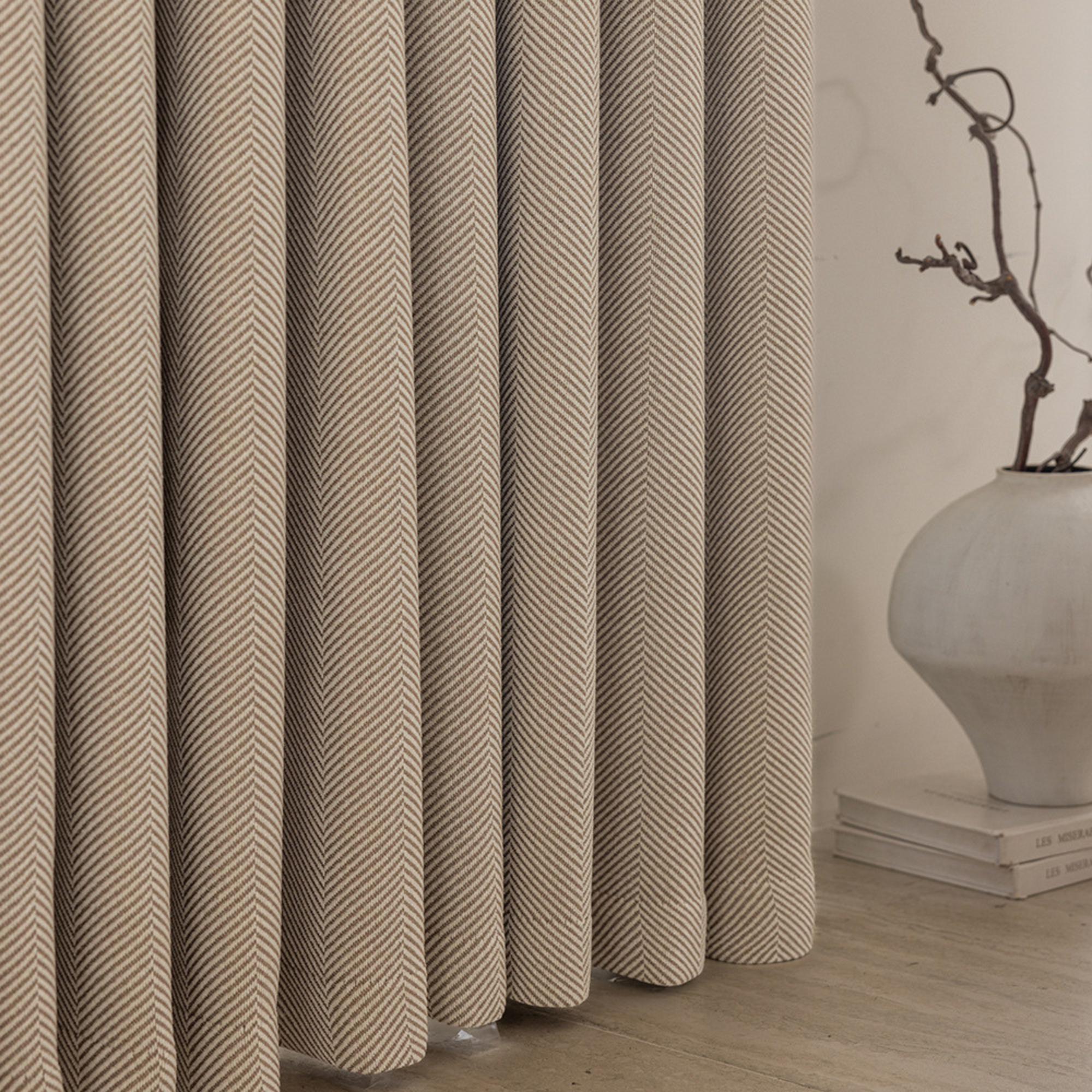 herringbone patterned curtains with a vase and branch decoration on a neutral background