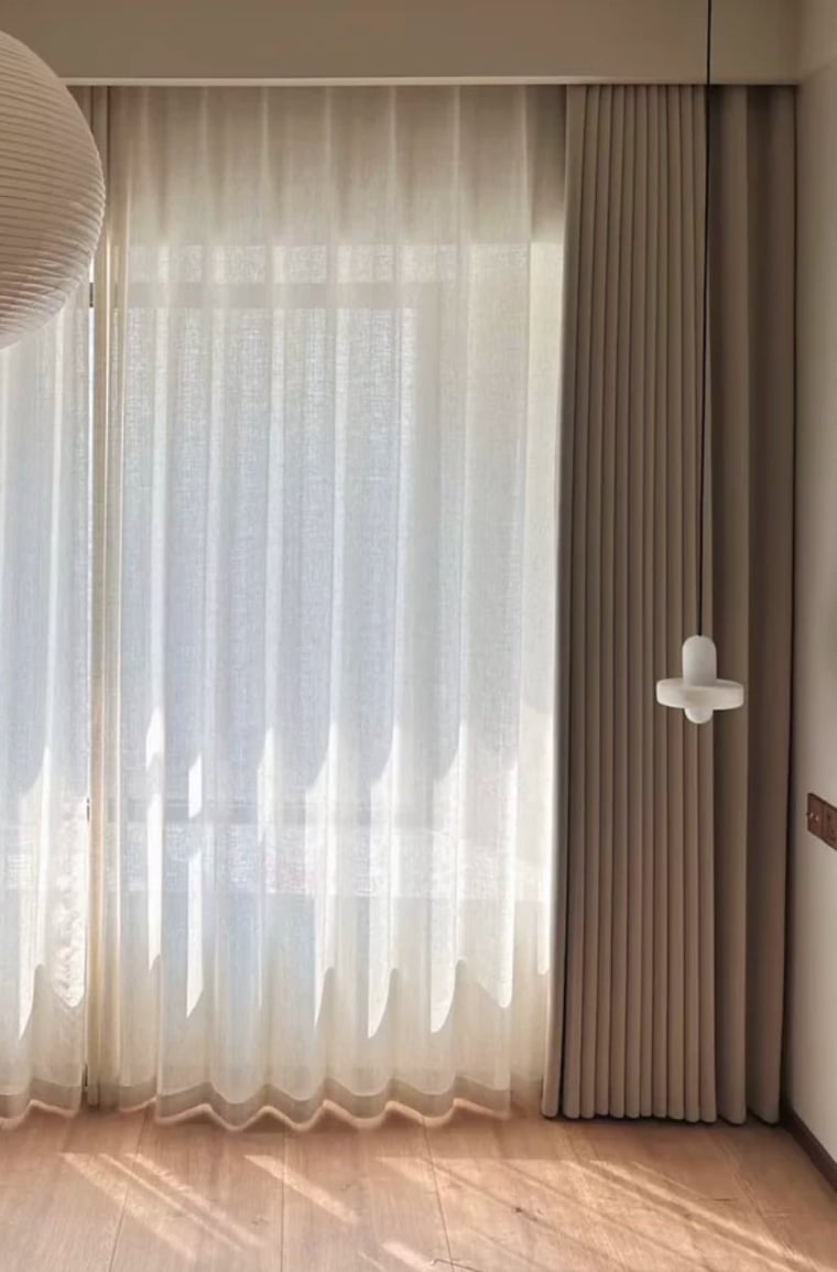 Sheer white curtain with a beige herringbone curtain panel in a room setting.