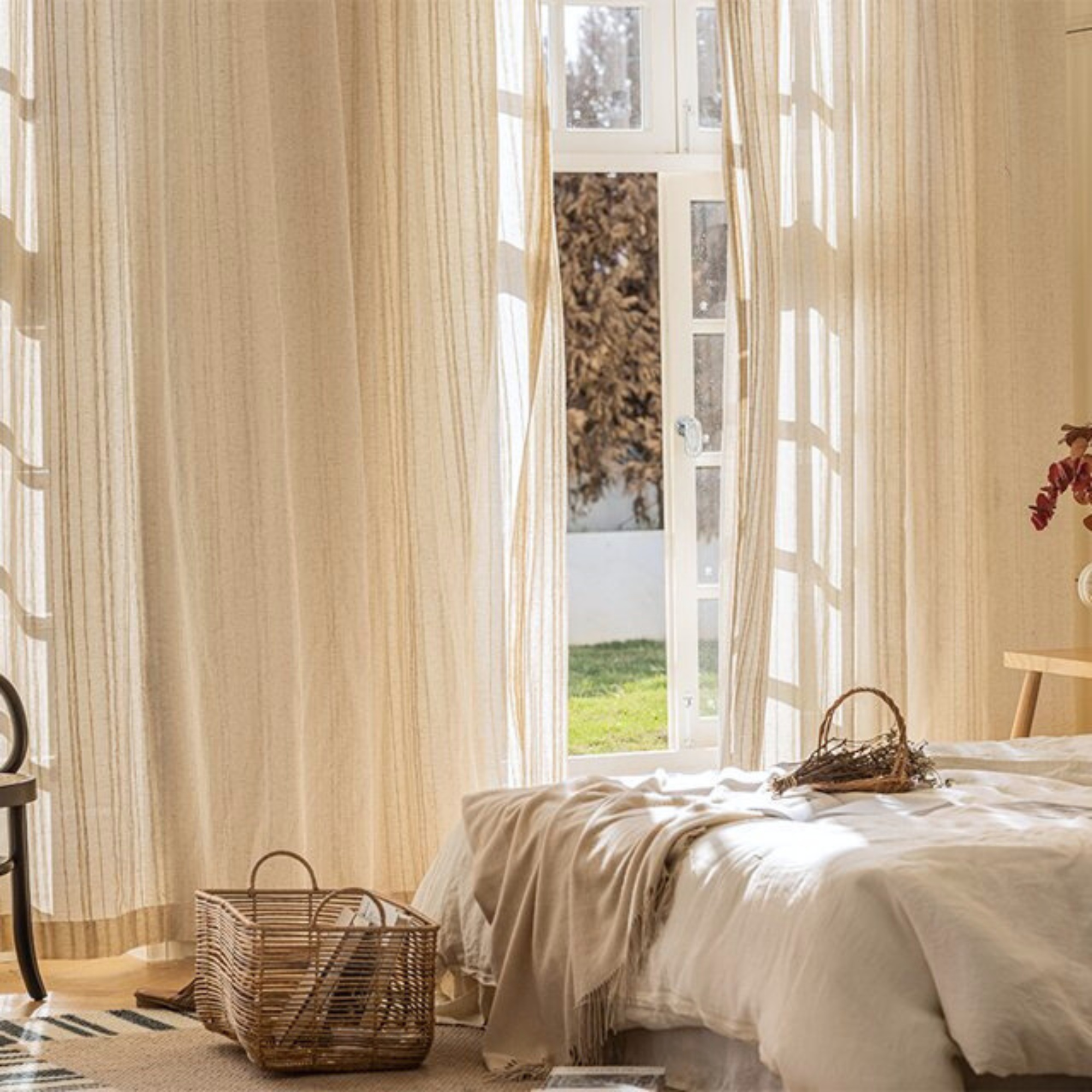 Bedroom with large windows, sheer linen curtains, and a basket on the floor.